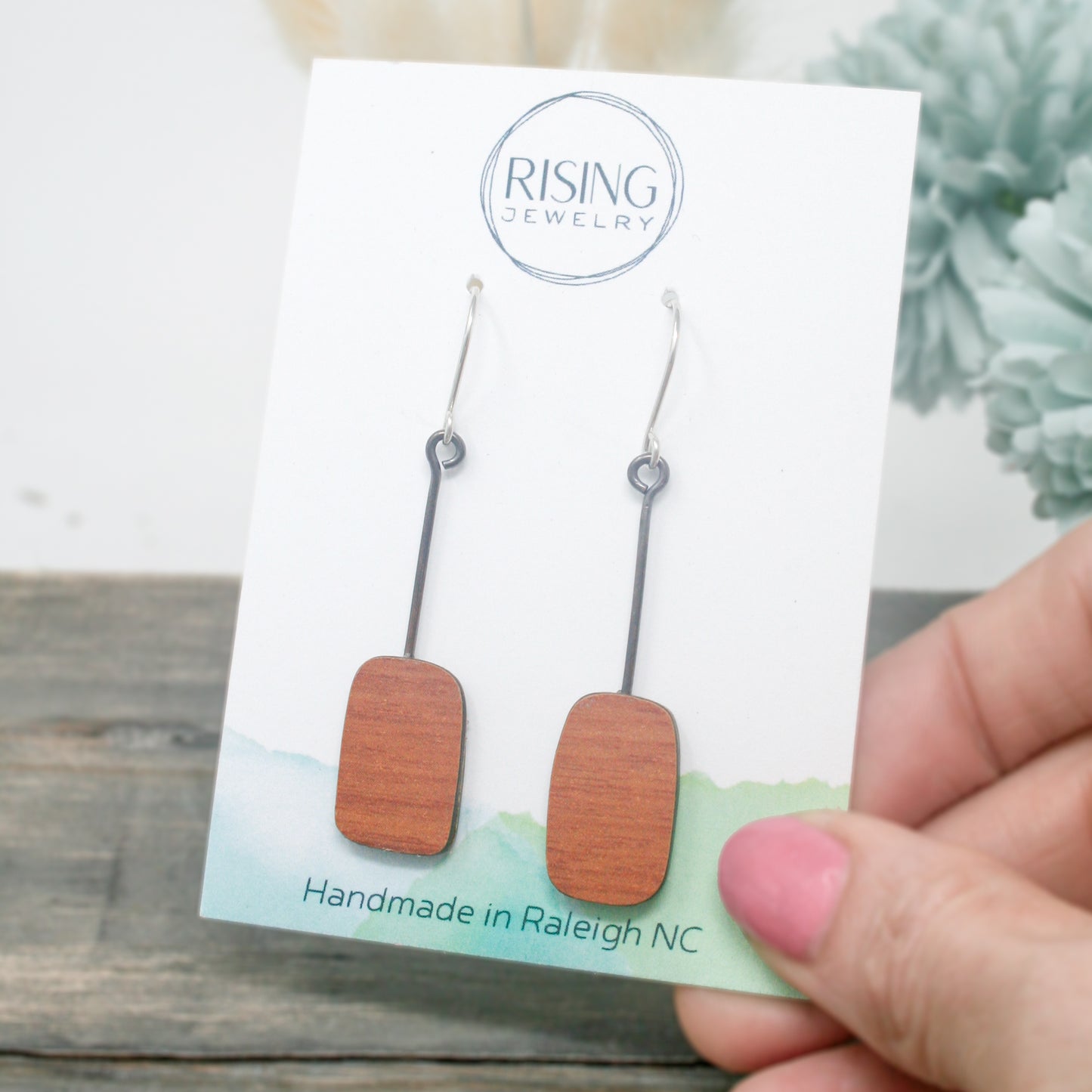 a hand holding a pair of wooden earrings