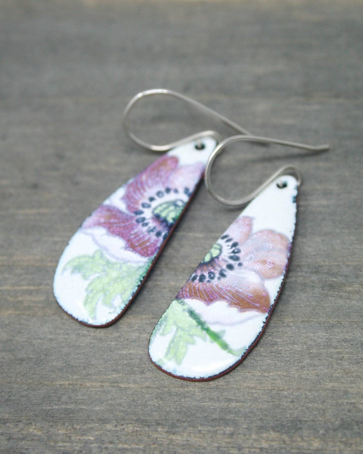 a pair of earrings with flowers painted on them