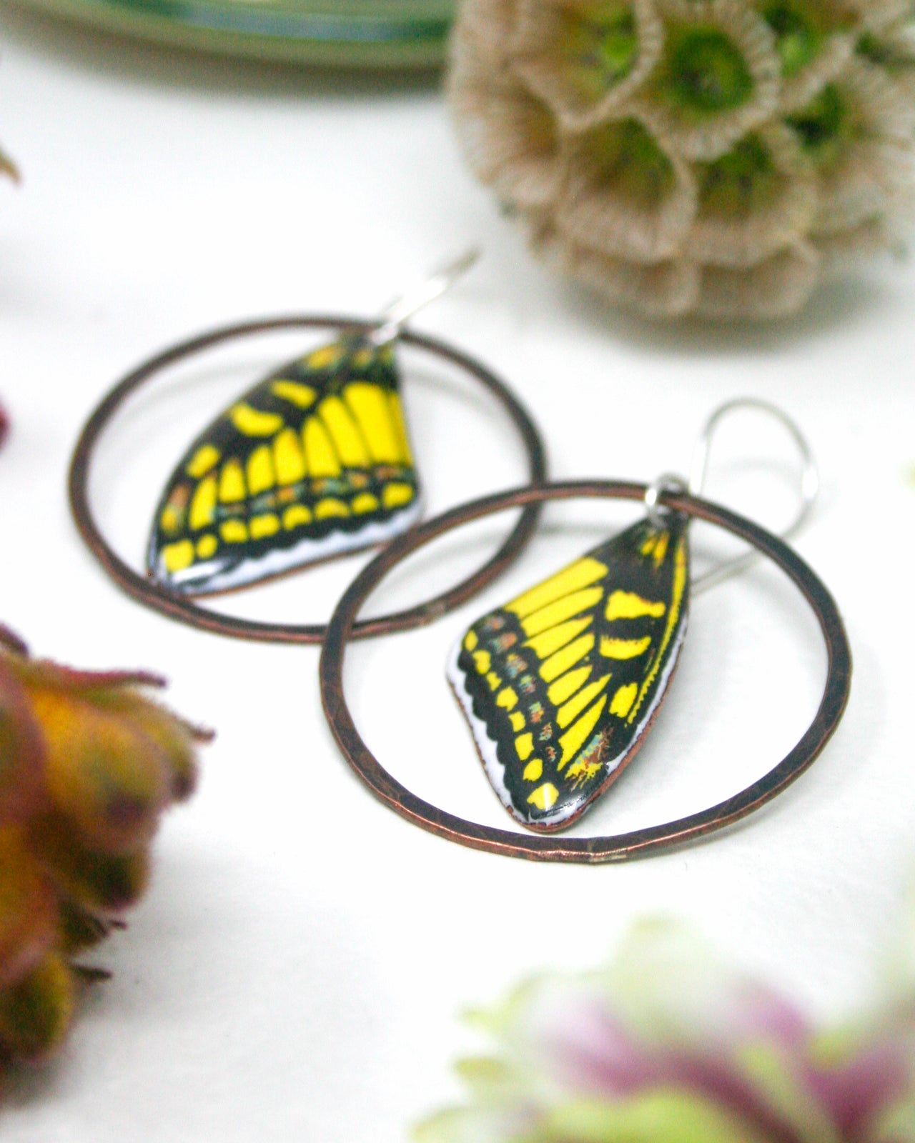 a pair of earrings with butterfly wing designs, placed on a white surface.