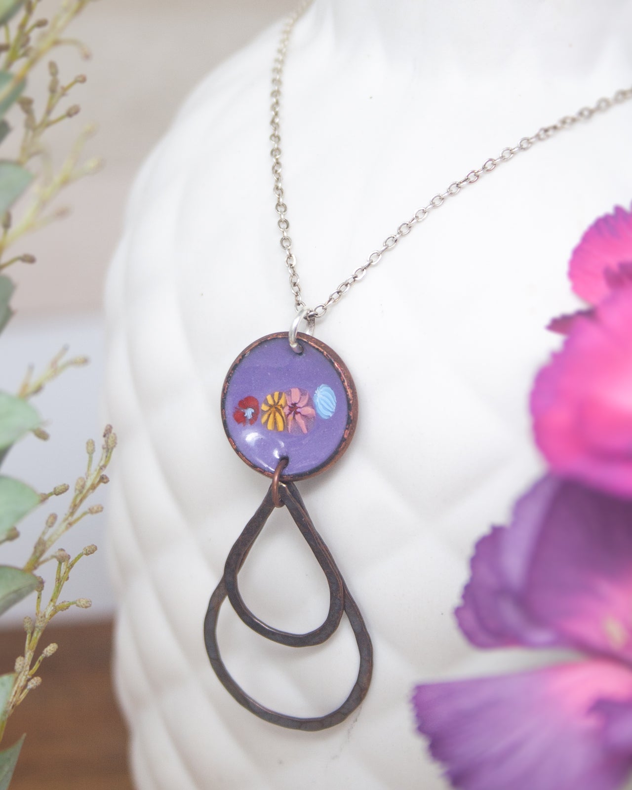 A necklace with a circular pendant featuring a floral design, hanging from a chain.