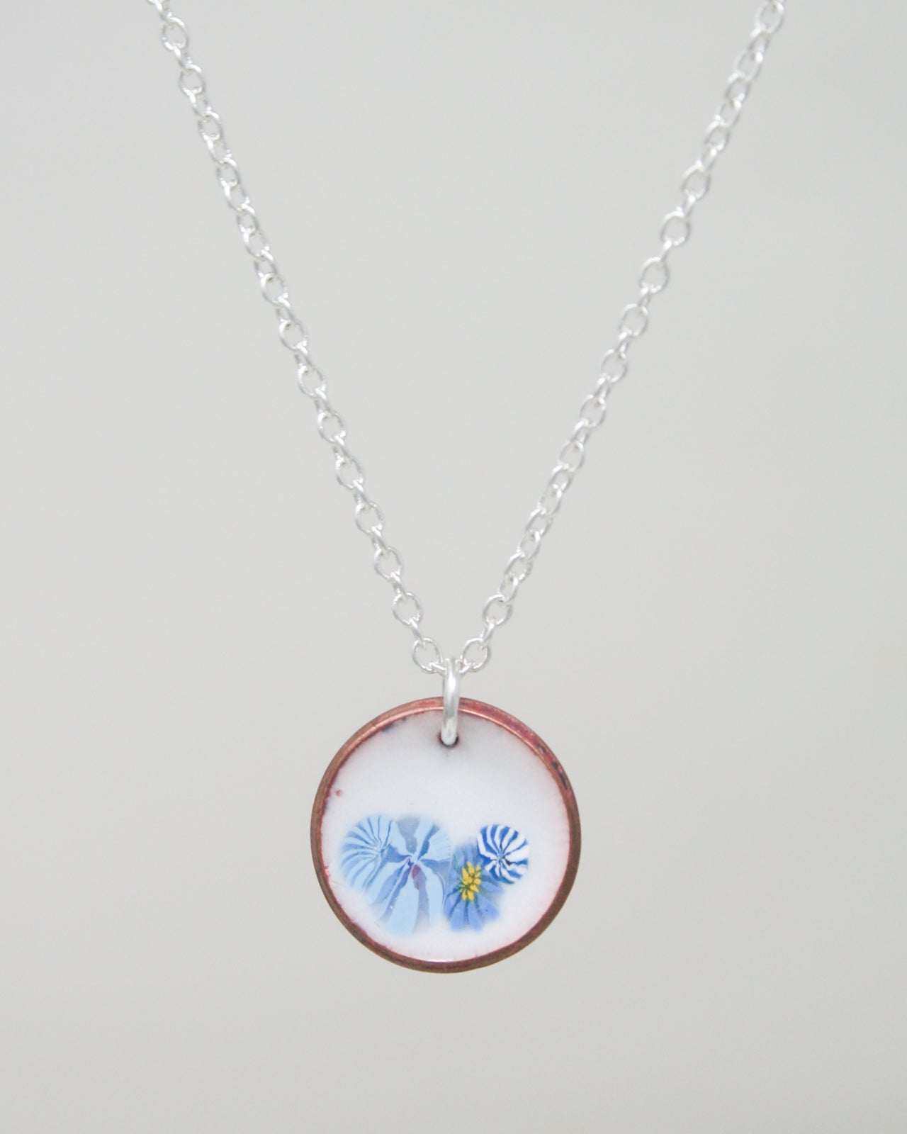 a white necklace with a blue flower on it