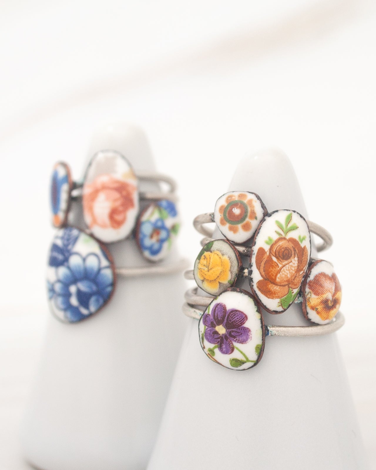 two white pedestals with colorful, floral-patterned rings on them.