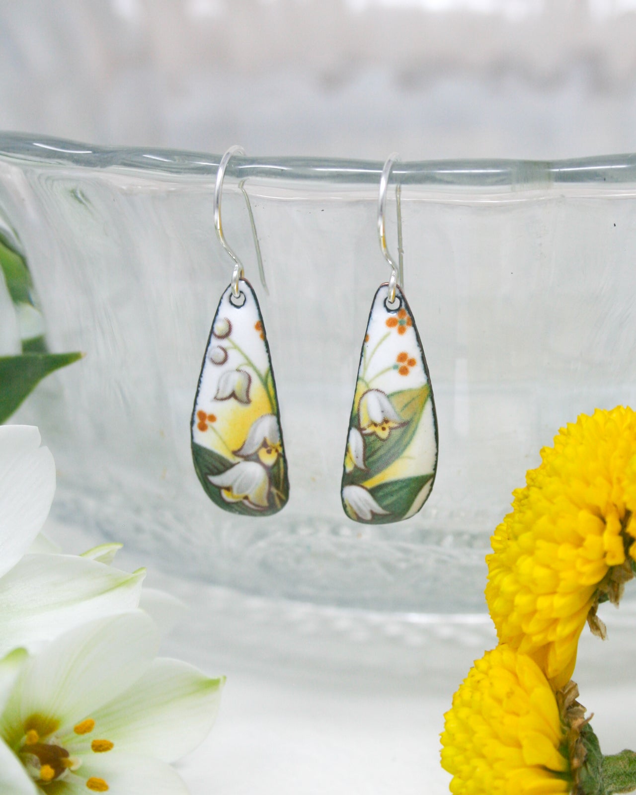 a close up of a pair of earrings near a flower