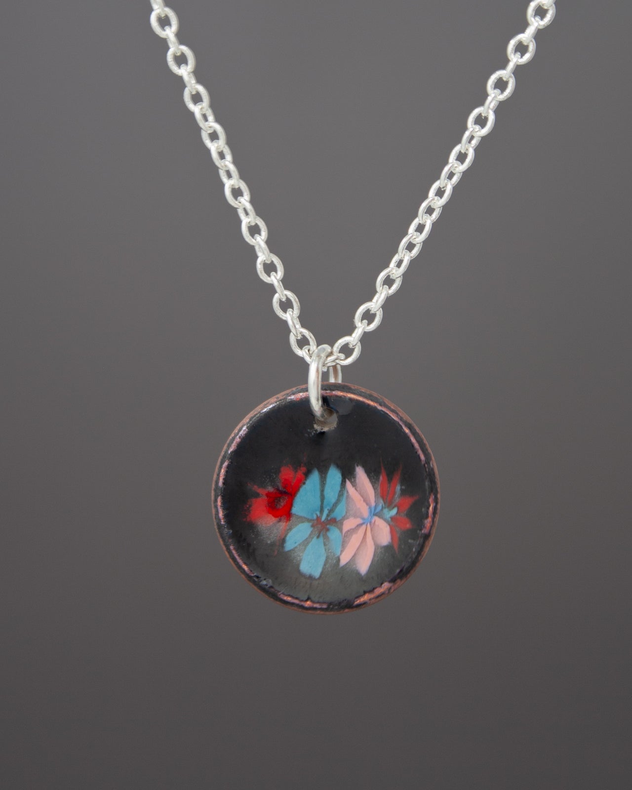 A necklace with a circular pendant featuring a floral design in various colors.
