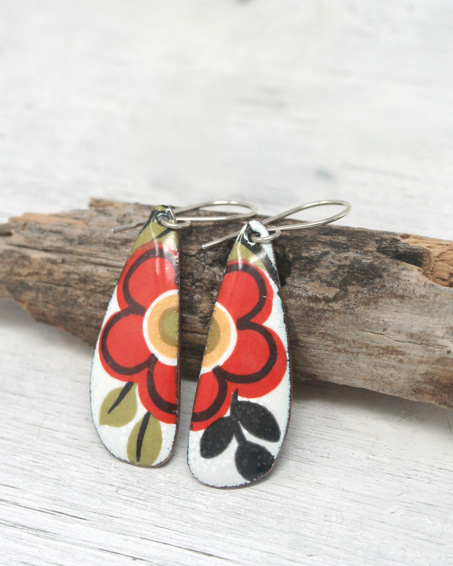 a pair of earrings sitting on top of a piece of wood