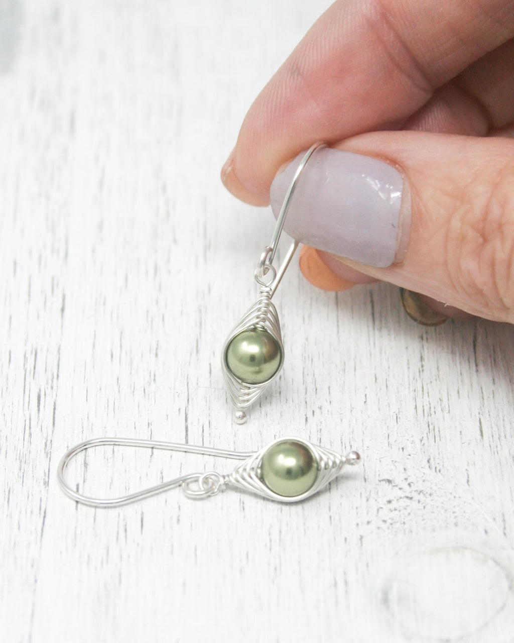 a person is holding a pair of earrings