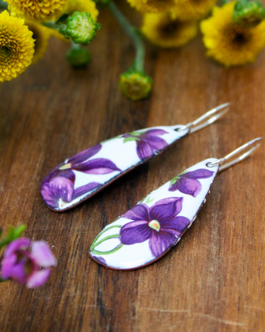a pair of purple flowers sitting on top of a wooden table