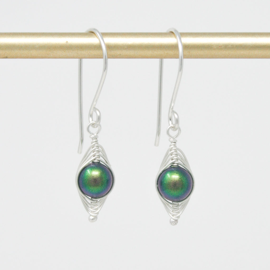 a pair of silver and green earrings hanging from a hook