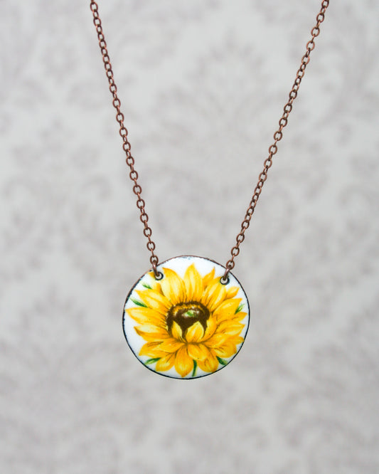 a yellow sunflower painted on a round glass pendant