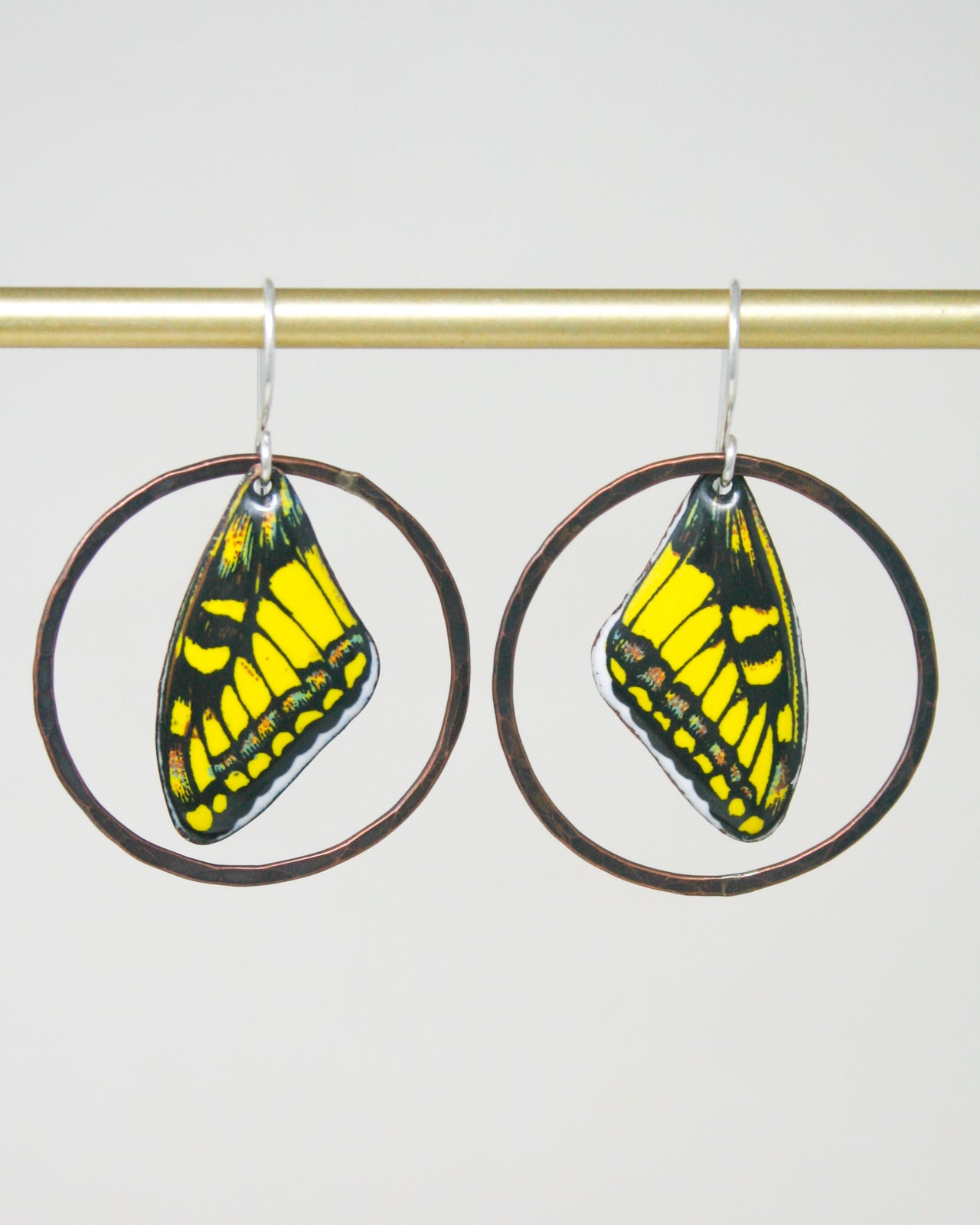 A pair of earrings with butterfly wing designs, featuring vibrant yellow and black colors.