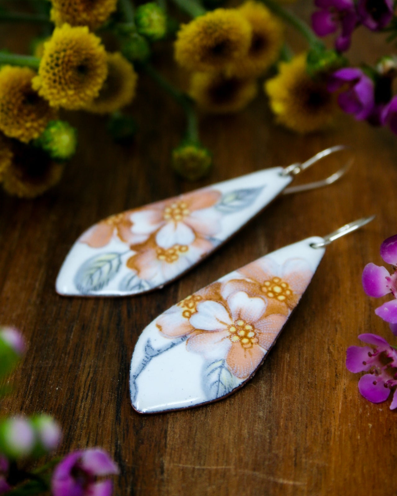 a pair of earrings sitting on top of a wooden table