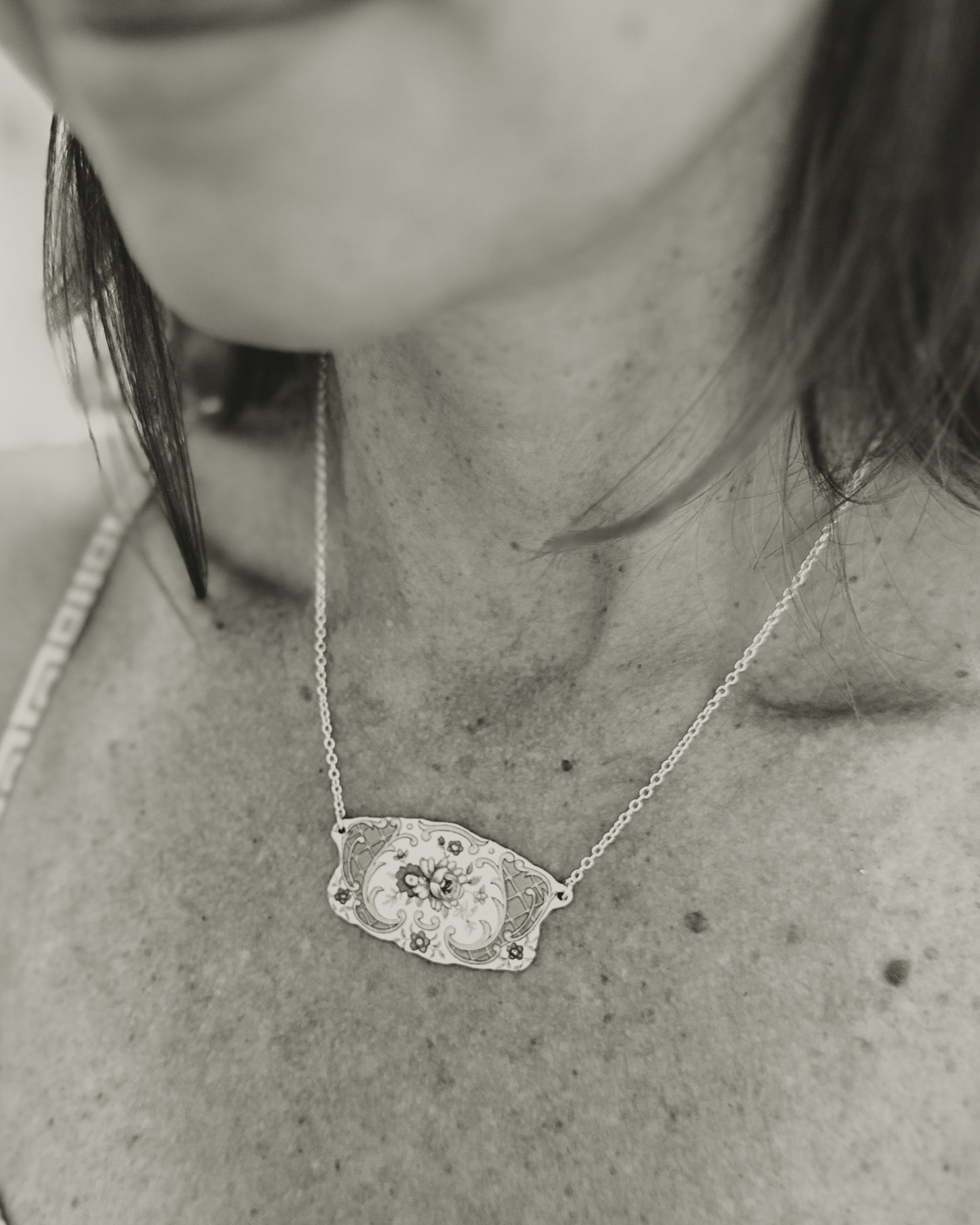 a black and white photo of a woman wearing a necklace