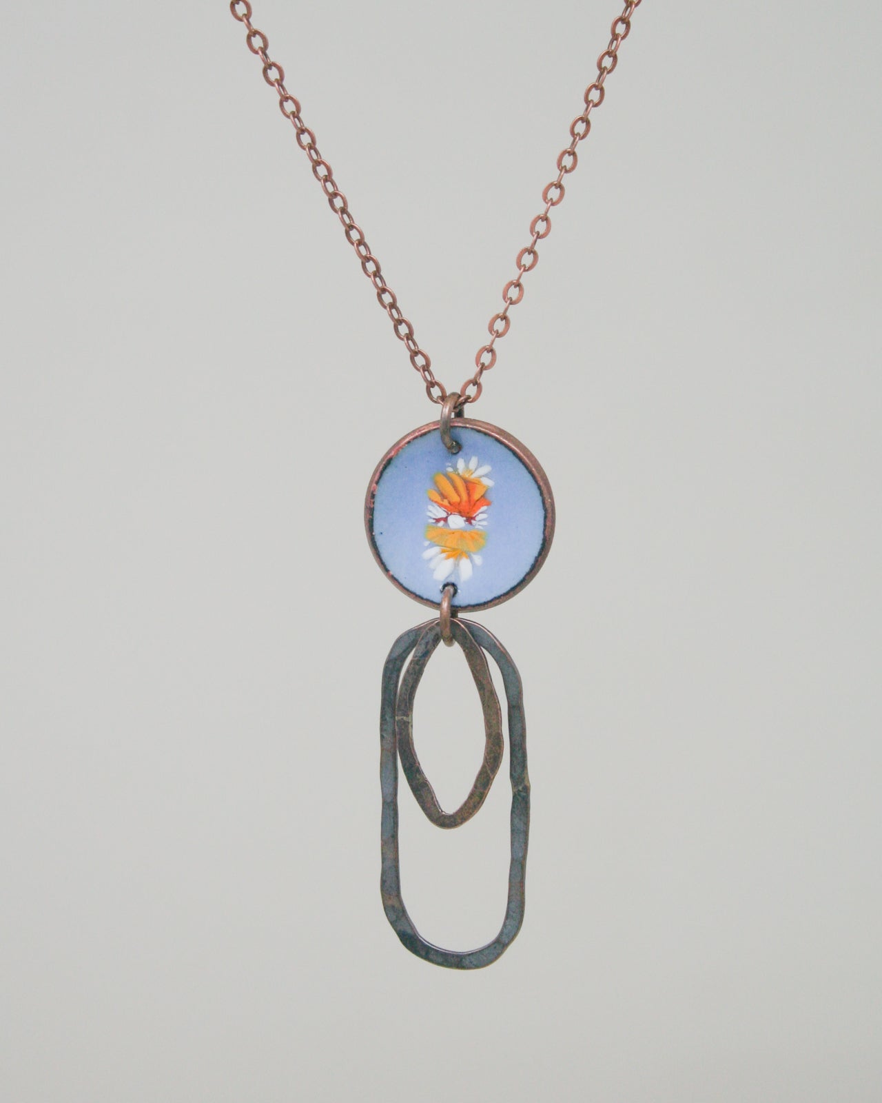 A necklace with a circular pendant featuring a floral design and a chain.