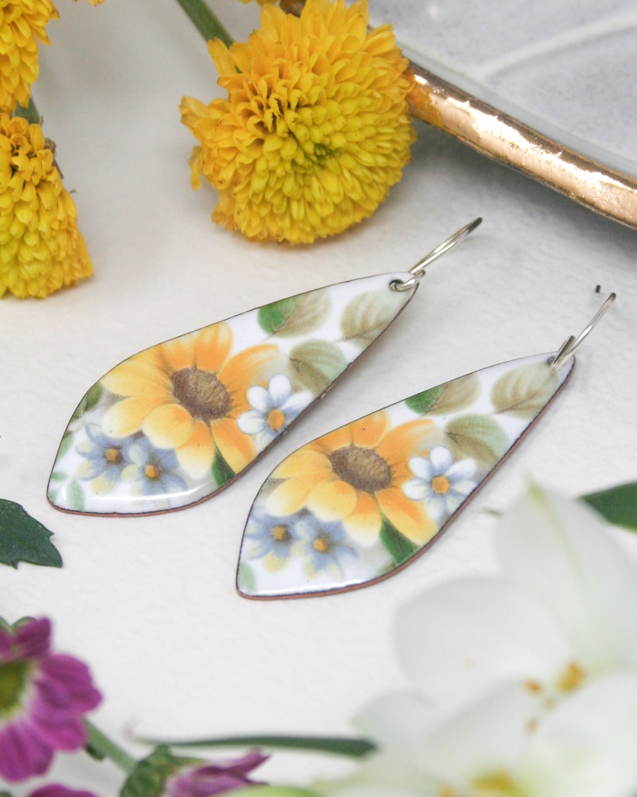 a pair of earrings with flowers painted on them