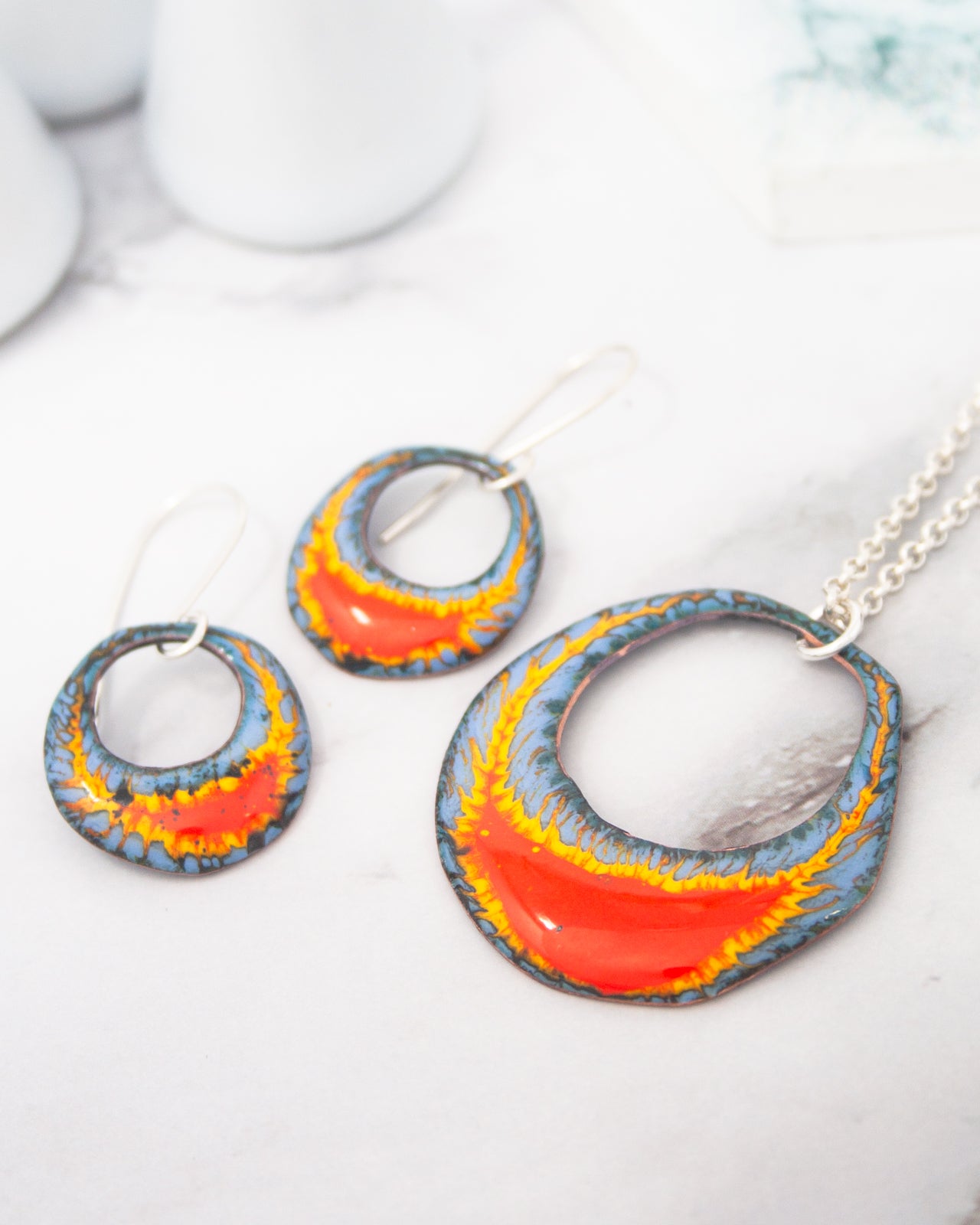 a necklace with a pendant and earrings with a circular design, both with a vibrant, colorful pattern.