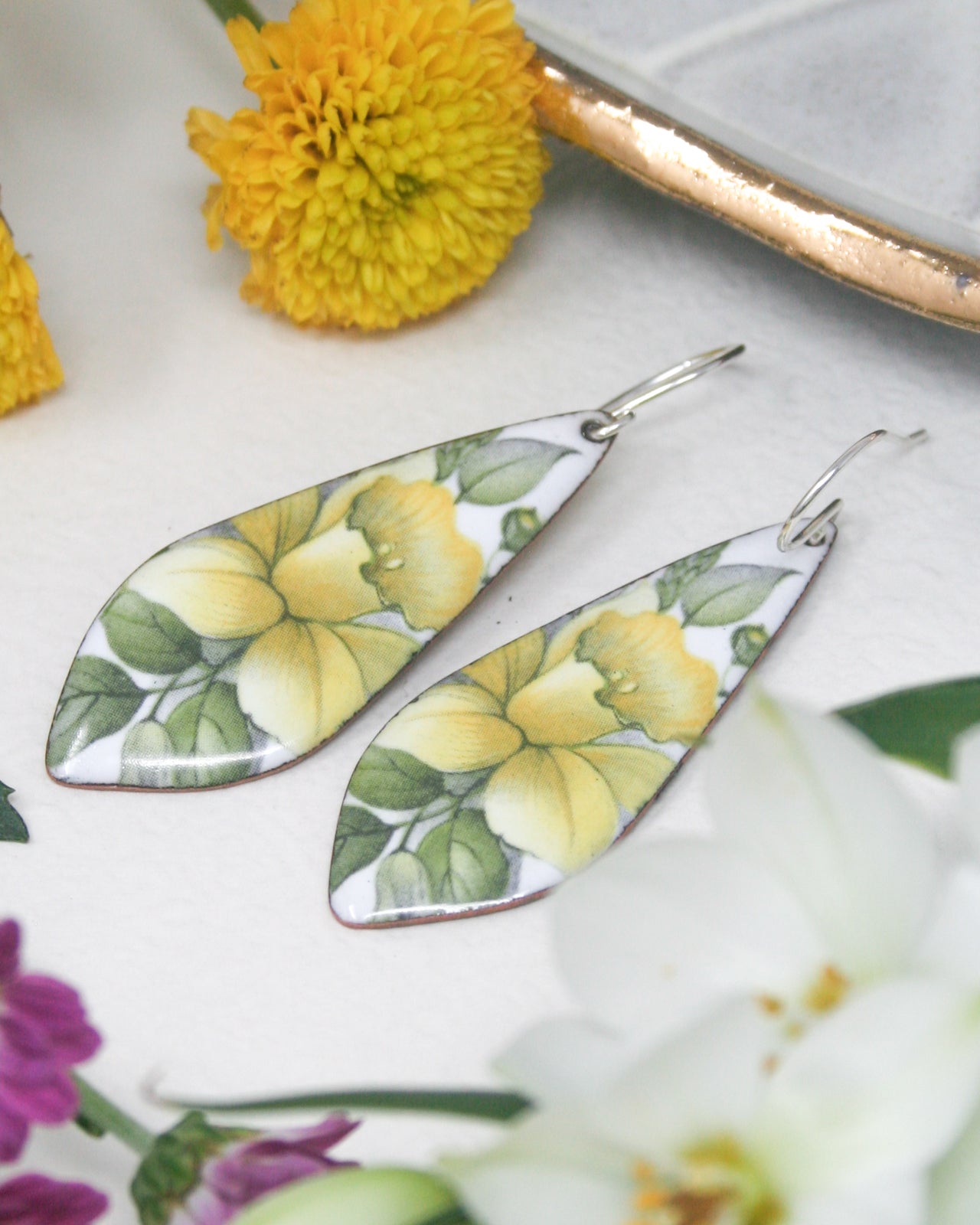 a pair of yellow and white flower earrings sitting on top of a table