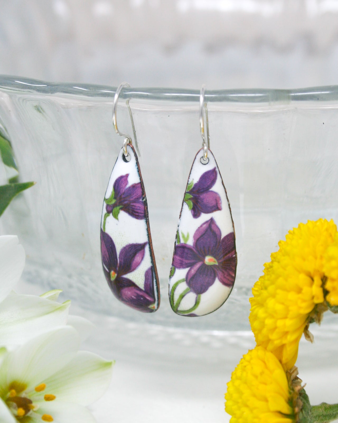 a close up of a pair of earrings near a flower