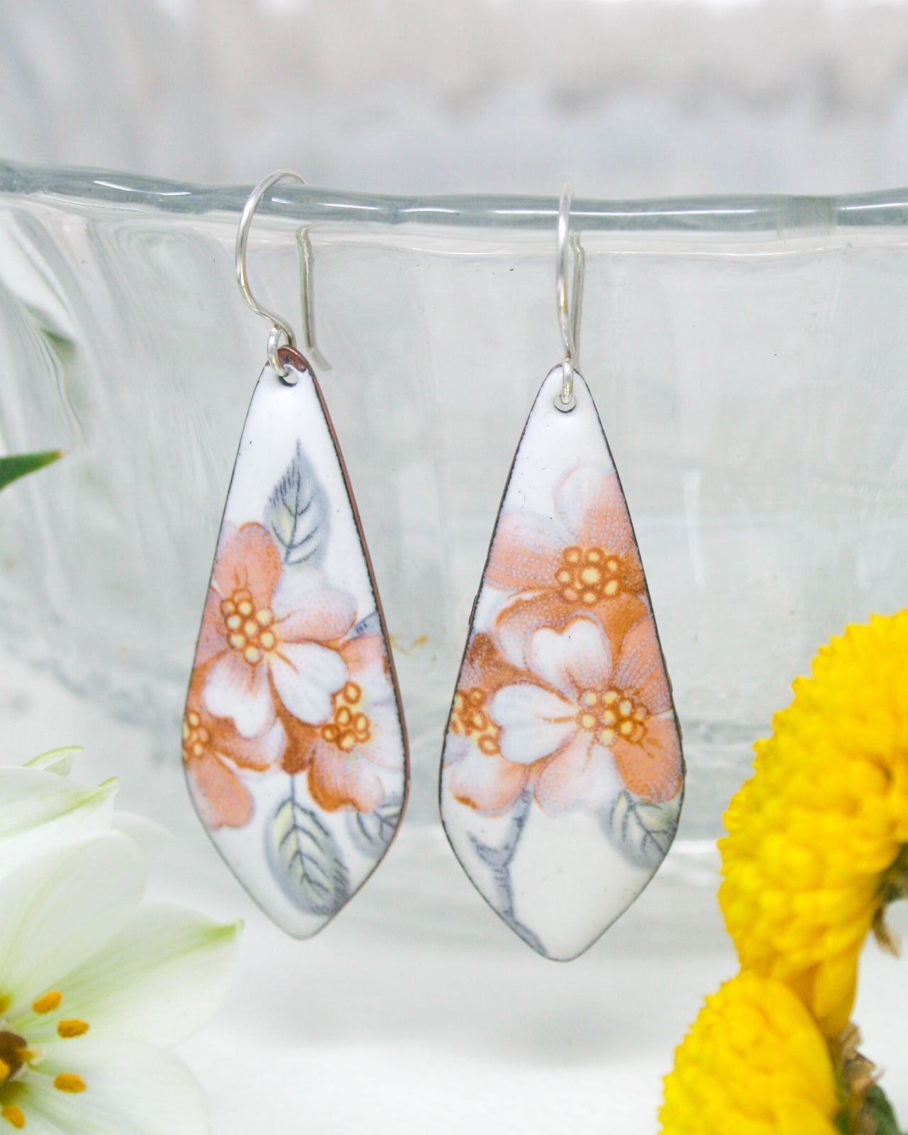 a pair of earrings with flowers painted on them