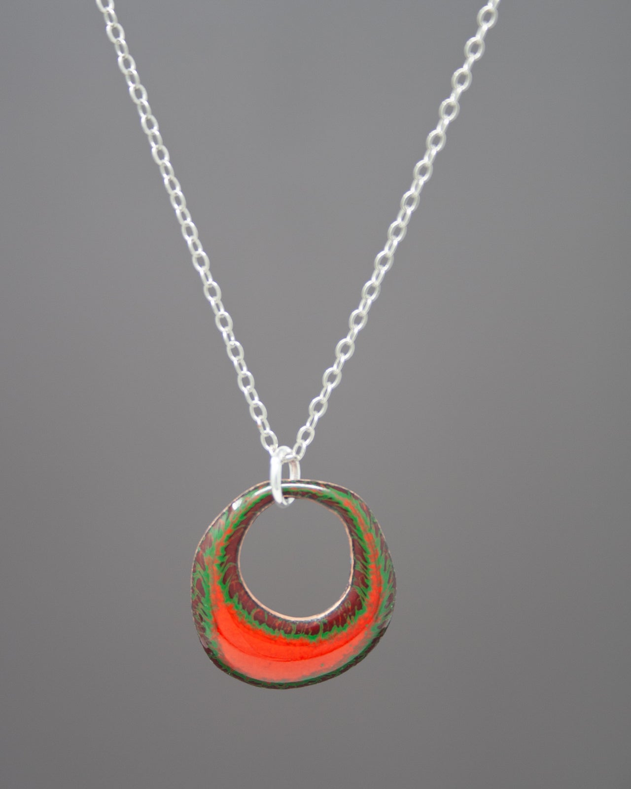 A necklace with a circular pendant featuring a vibrant red and green design.