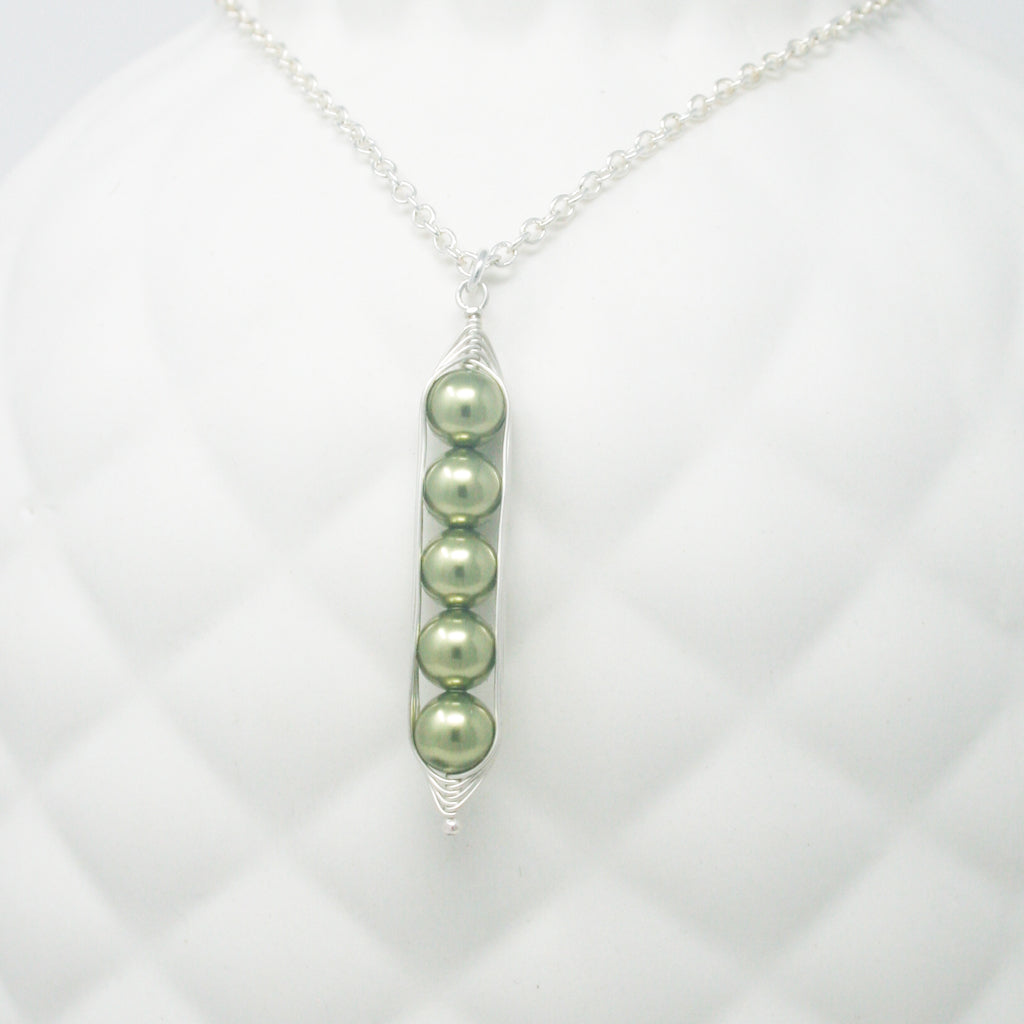 a necklace with three peas hanging from it