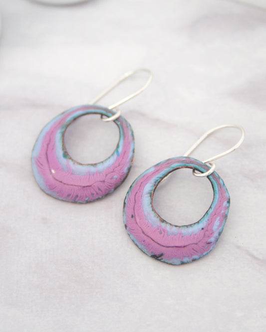 A pair of earrings with a unique, colorful design, featuring a combination of pink and blue hues.