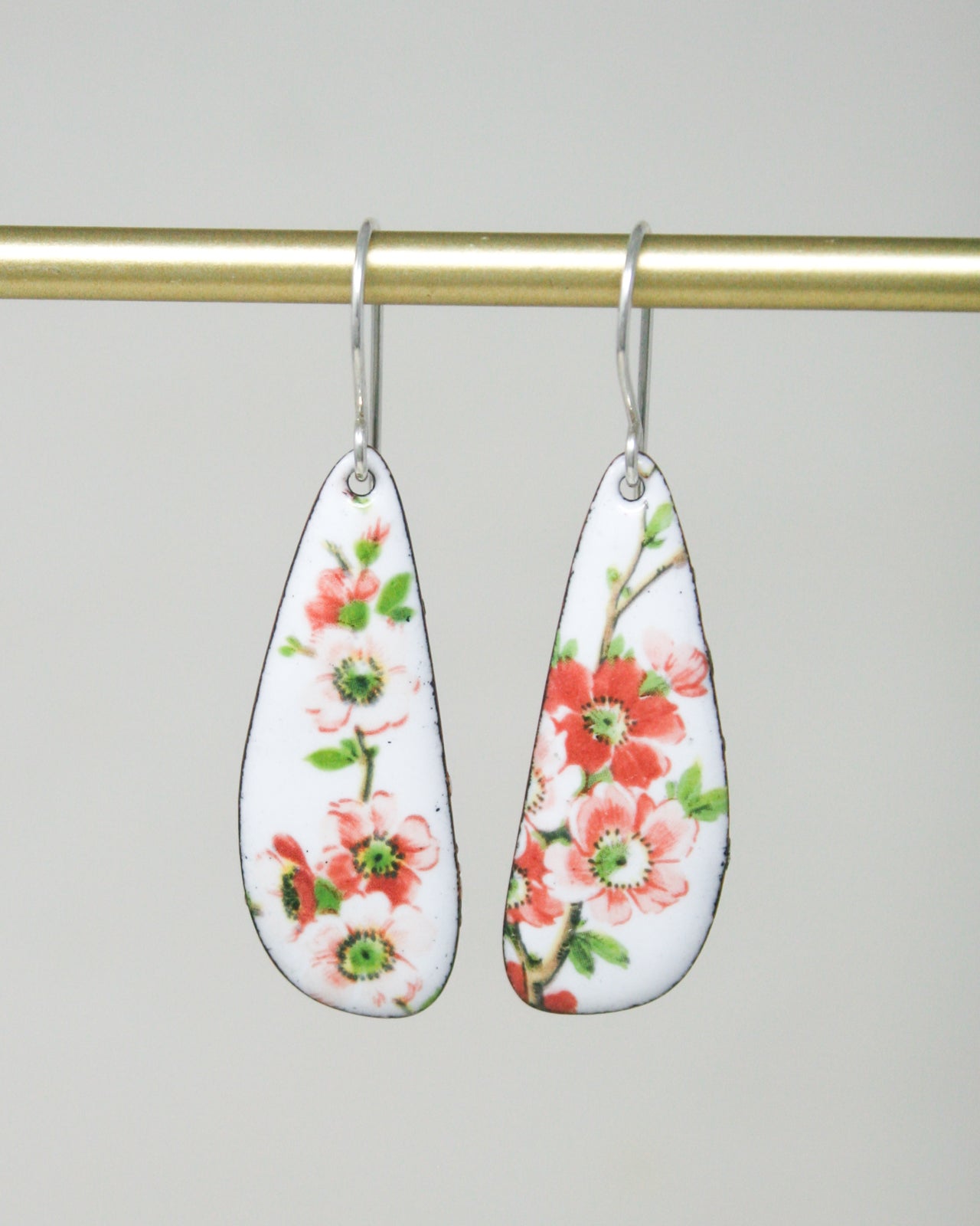 a pair of earrings hanging from a gold bar