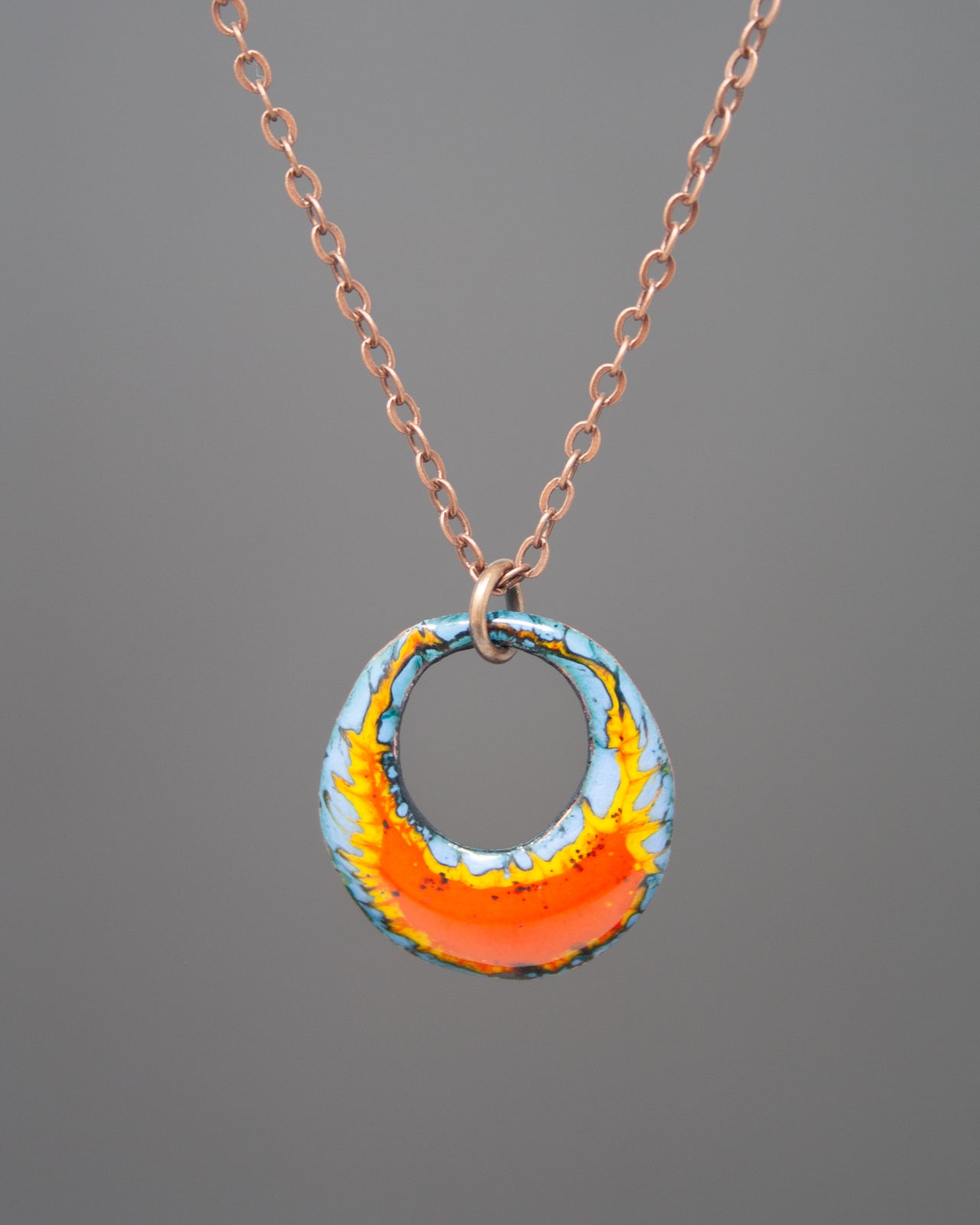 A necklace with a pendant featuring a colorful, abstract design in shades of blue, orange, and yellow.