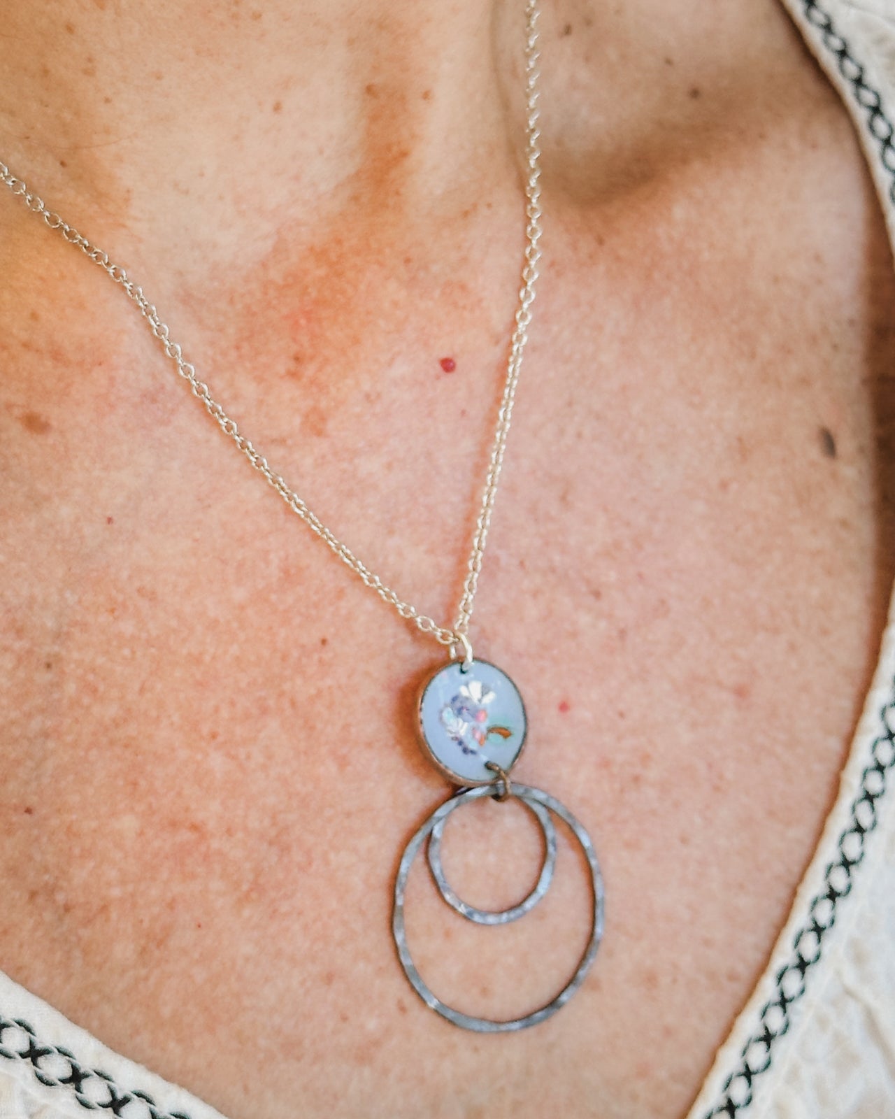 A silver necklace with a pendant featuring a flower design.