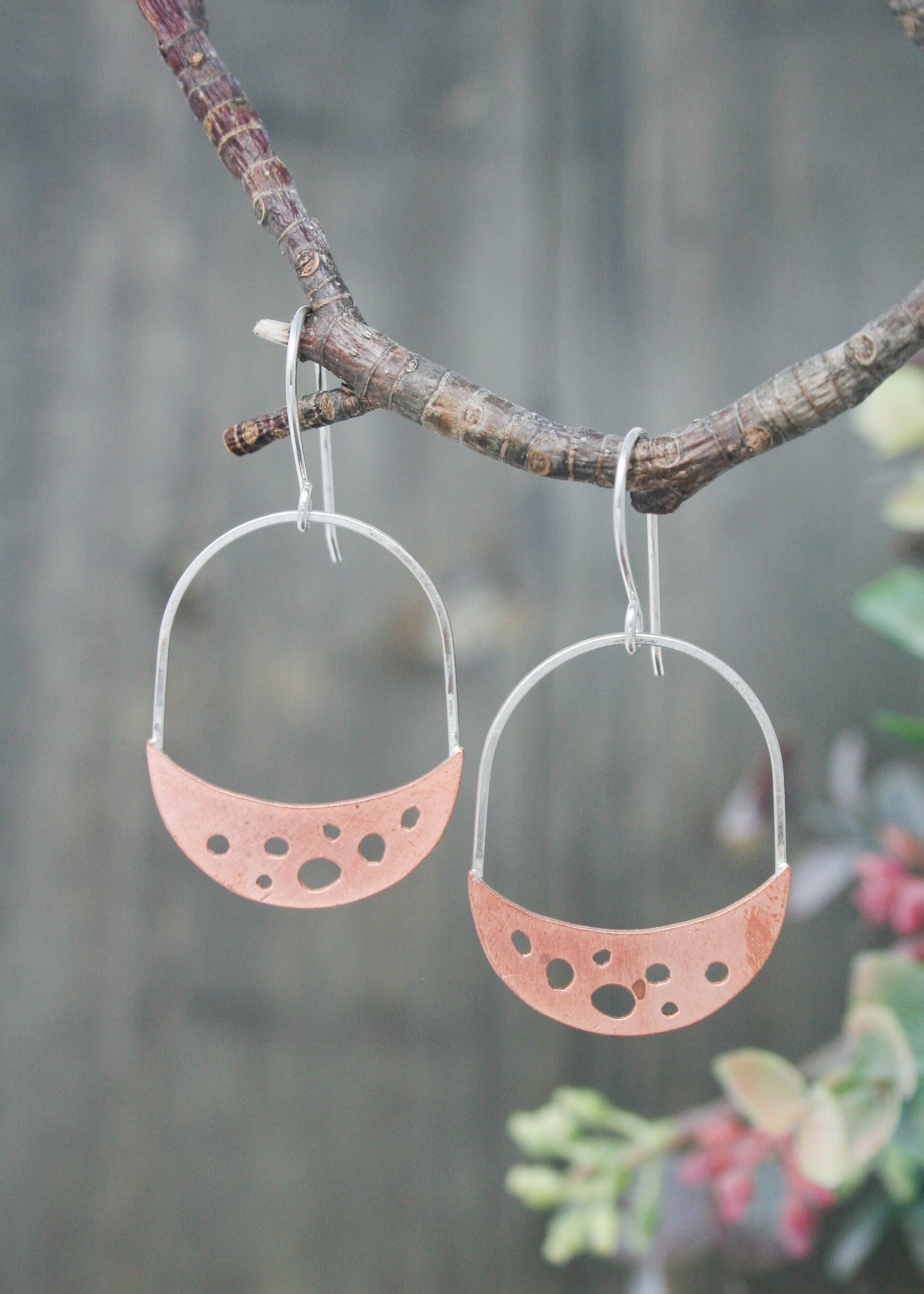 a pair of earrings hanging from a tree branch