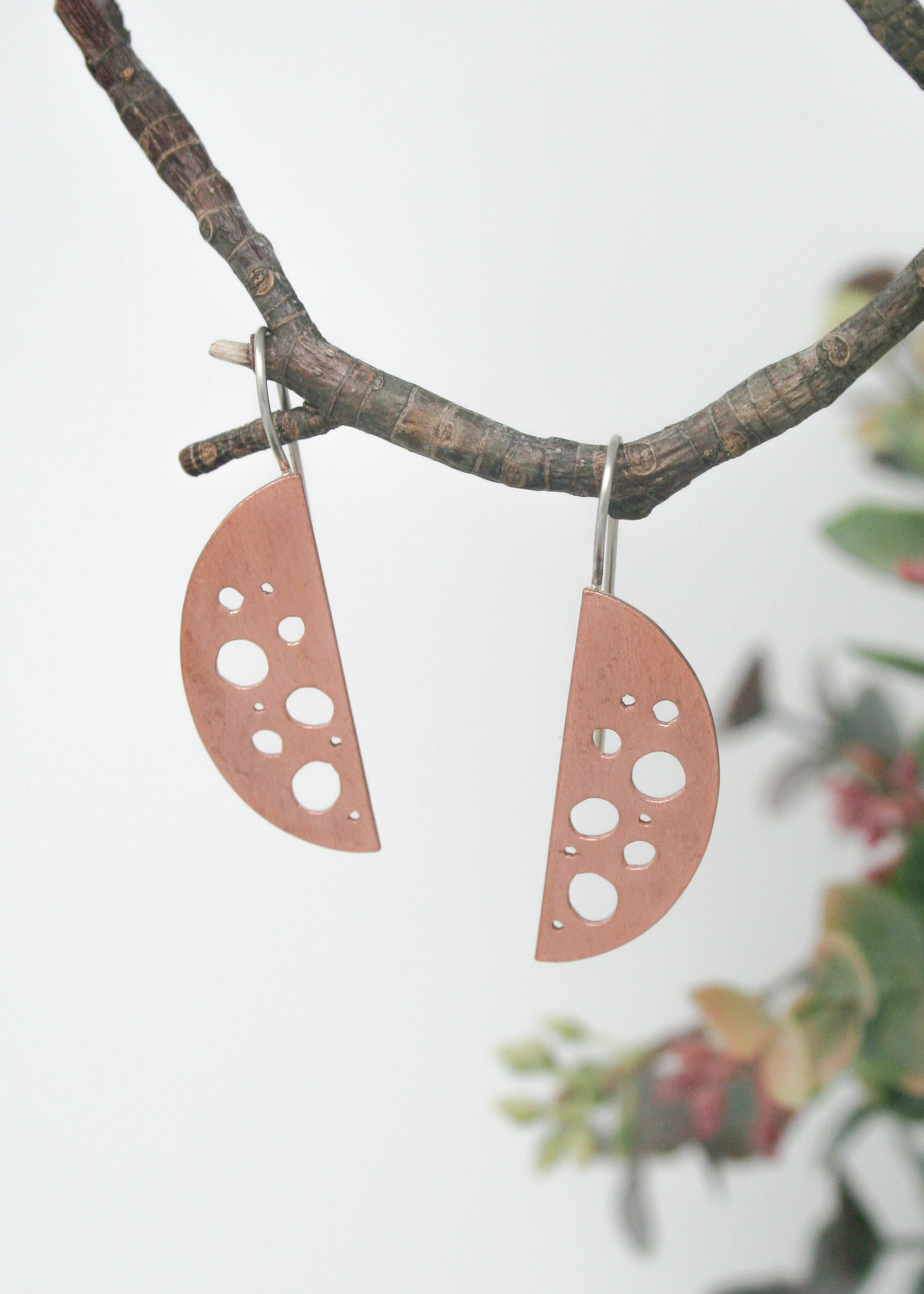 a pair of earrings hanging from a tree branch