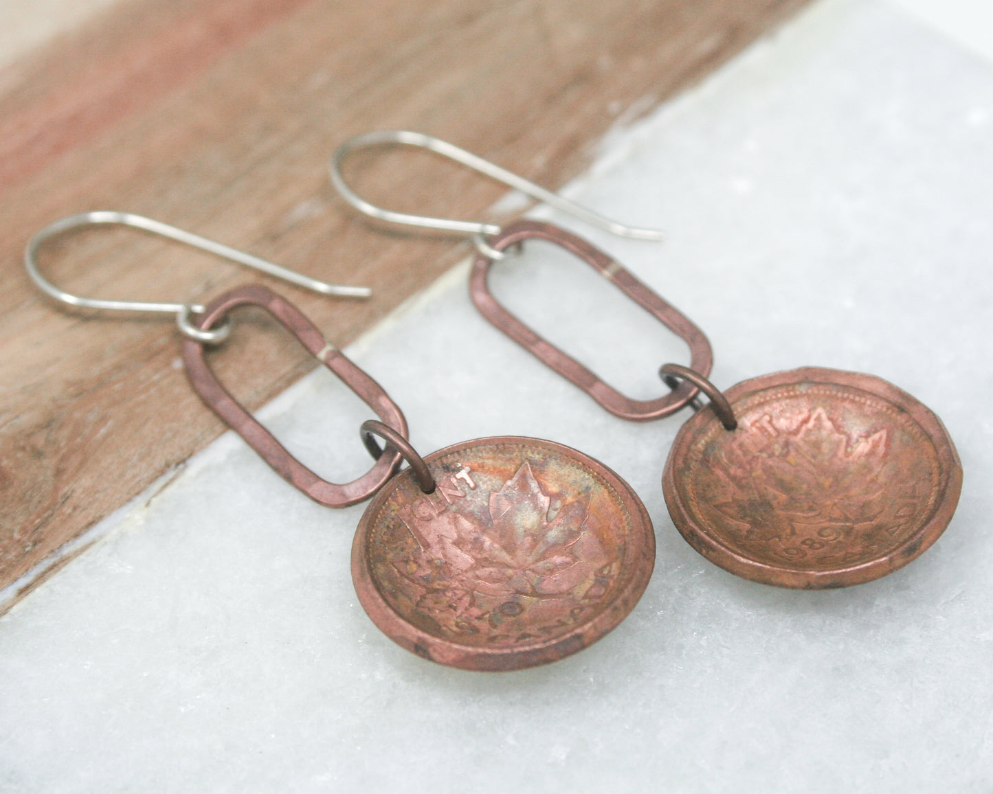 a pair of earrings sitting on top of a piece of wood