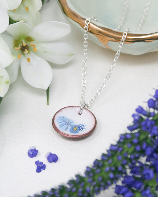a necklace with a picture of a blue flower on it