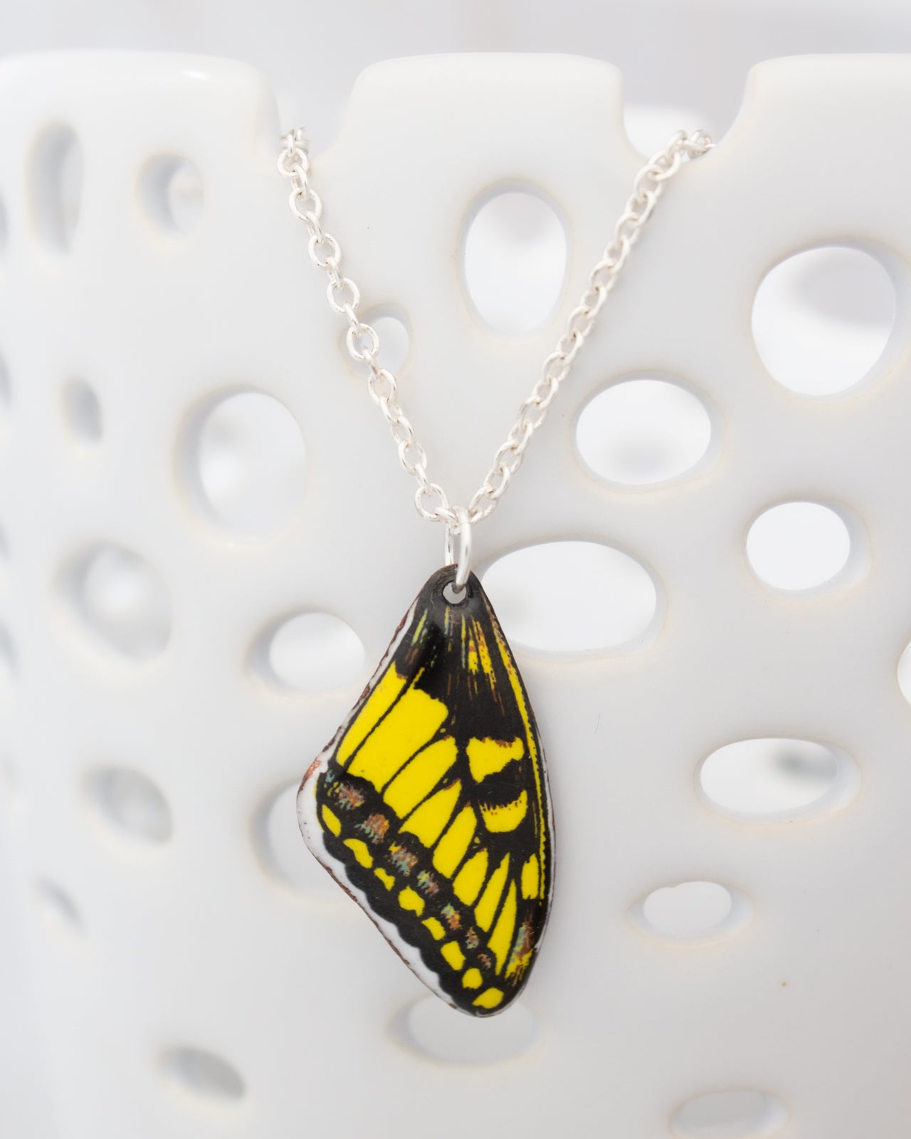 A necklace with a pendant featuring a yellow and black butterfly wing design.