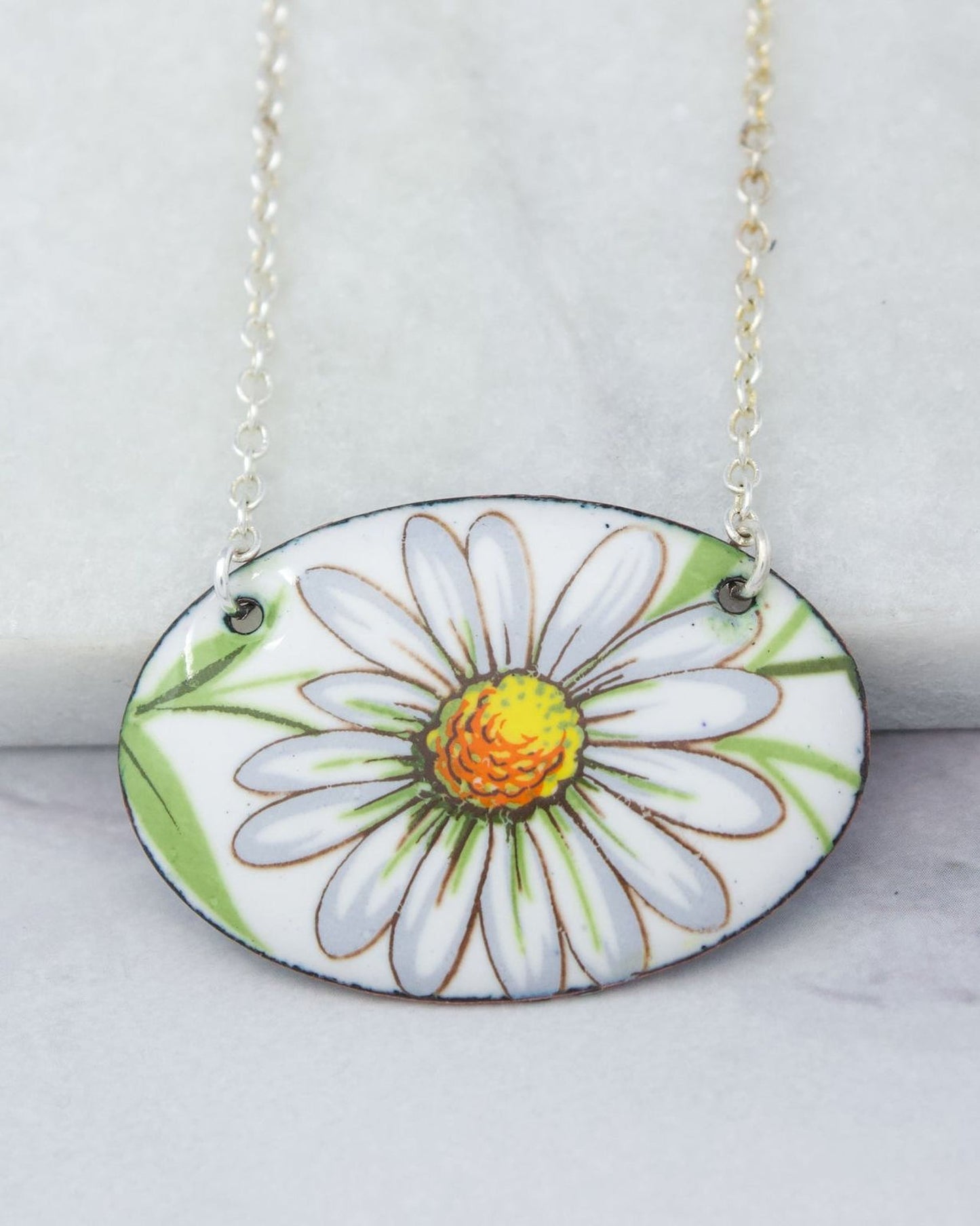 A necklace with a pendant featuring a white daisy flower design.
