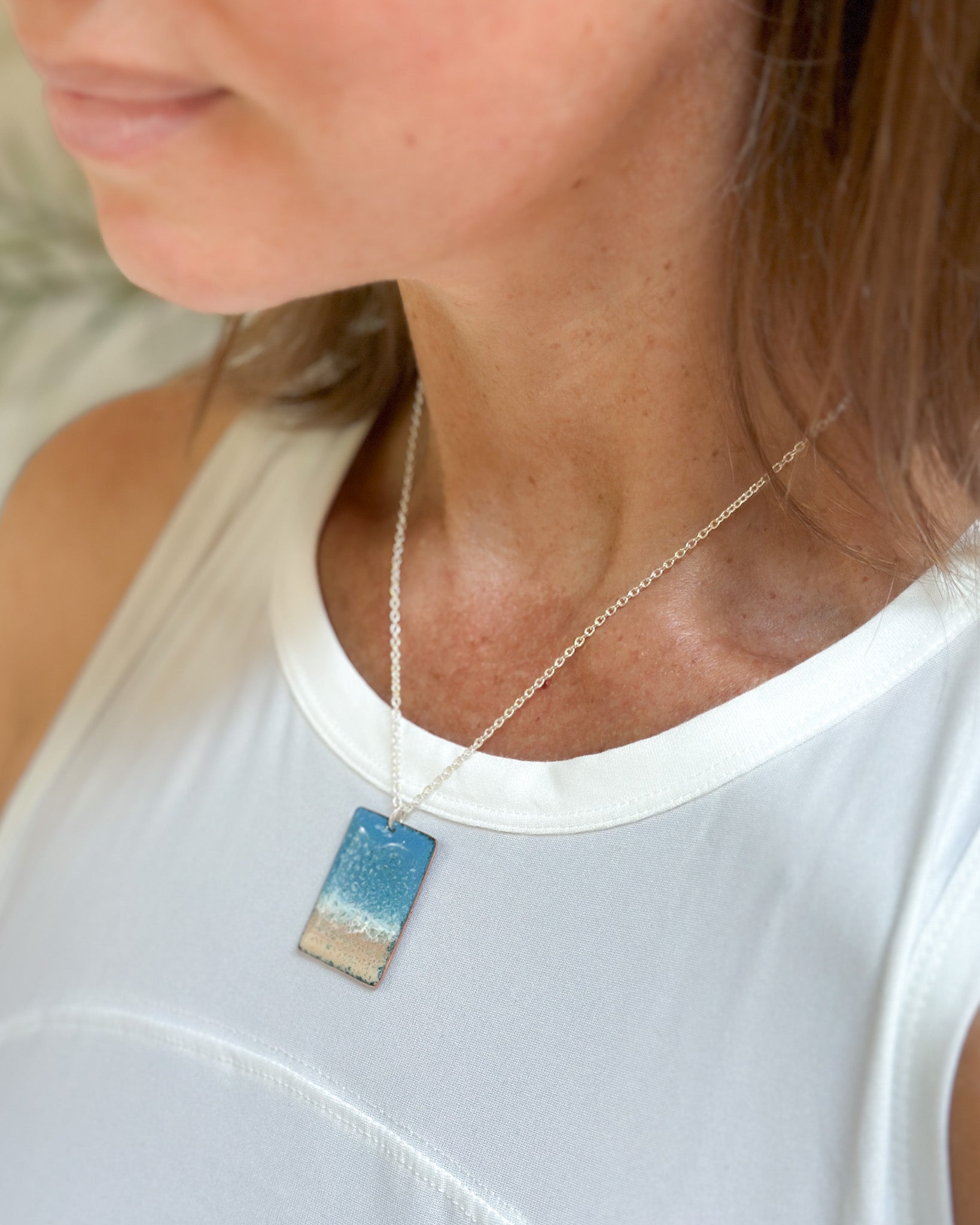 a woman wearing a white shirt and a blue and white necklace