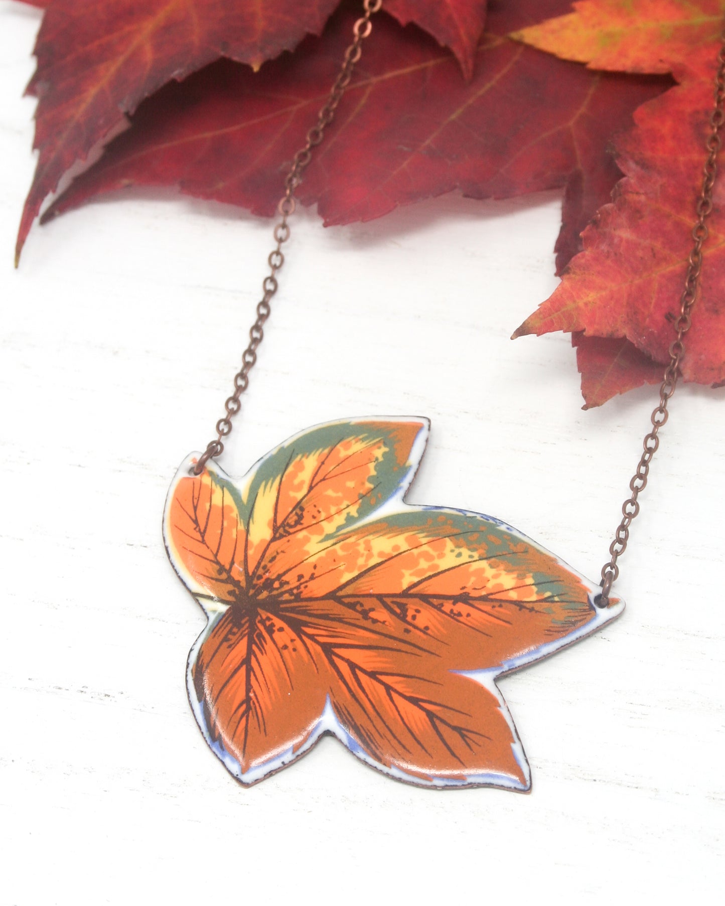 a necklace with an orange and yellow leaf on it