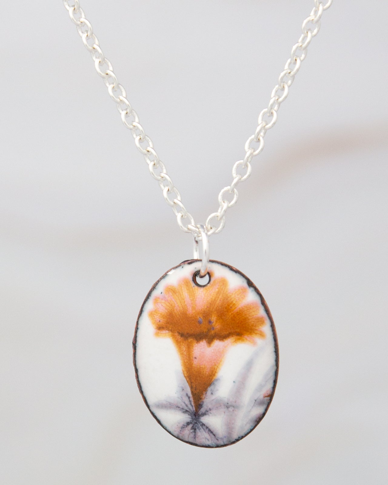 A silver necklace with a pendant featuring a colorful flower design.