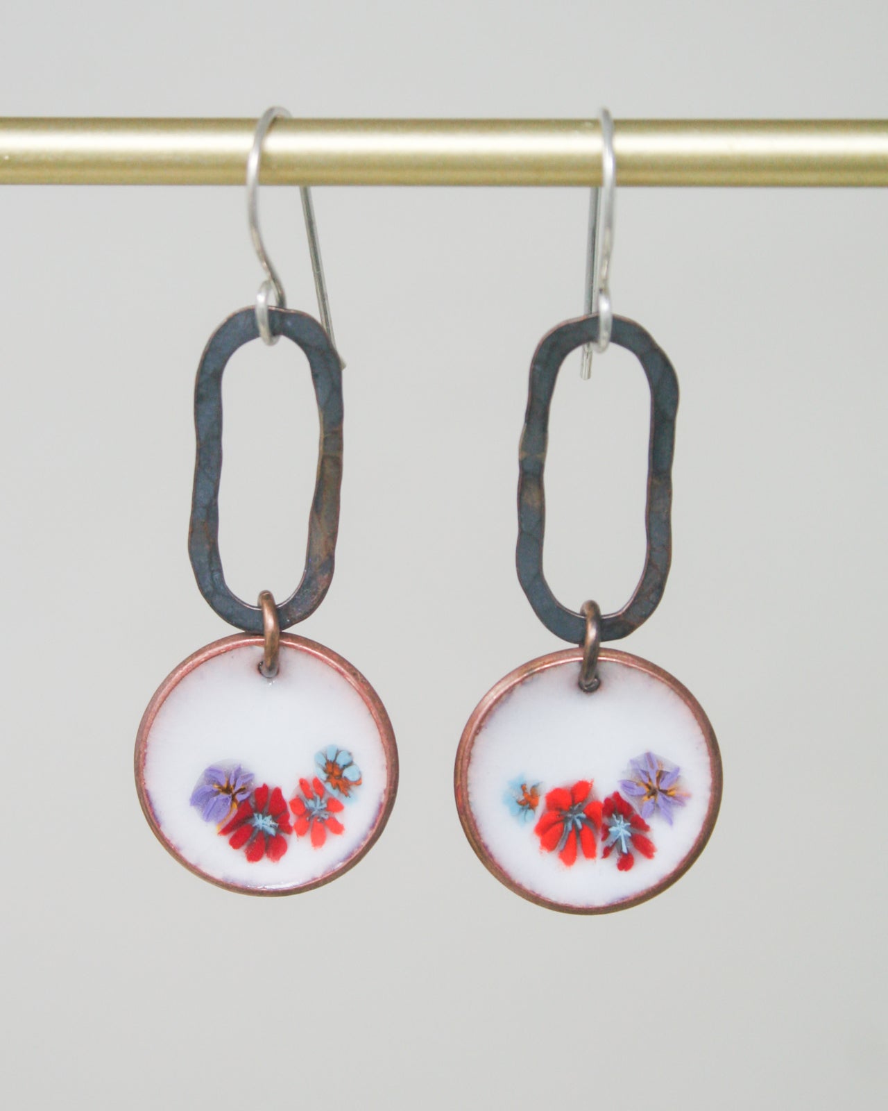 a pair of earrings with flowers painted on them