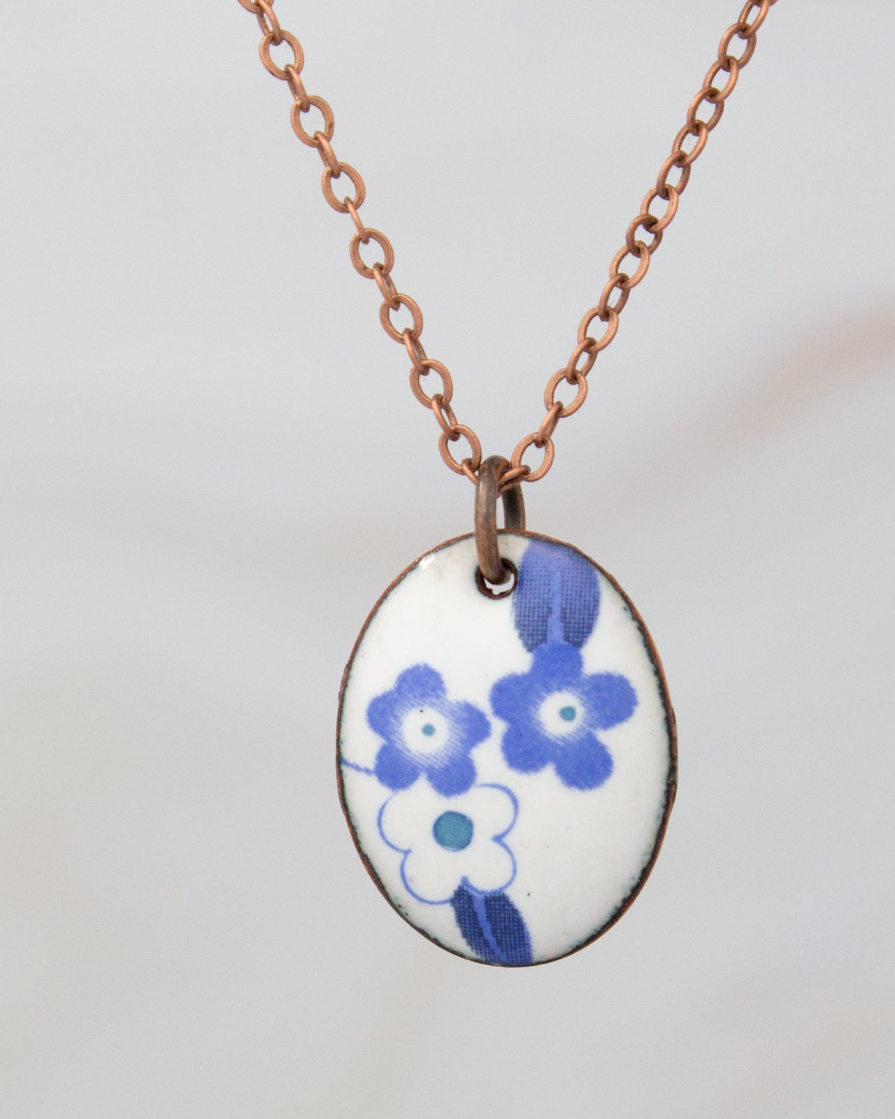 A necklace with a pendant featuring a blue floral design.