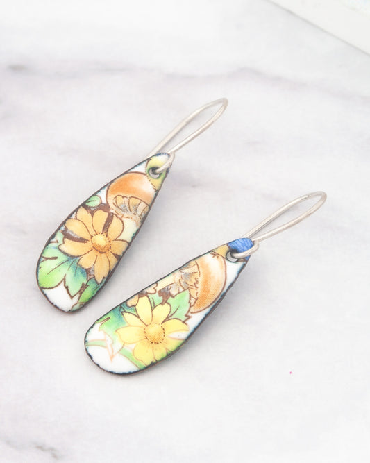 A pair of earrings with a floral design, featuring yellow flowers and green leaves.