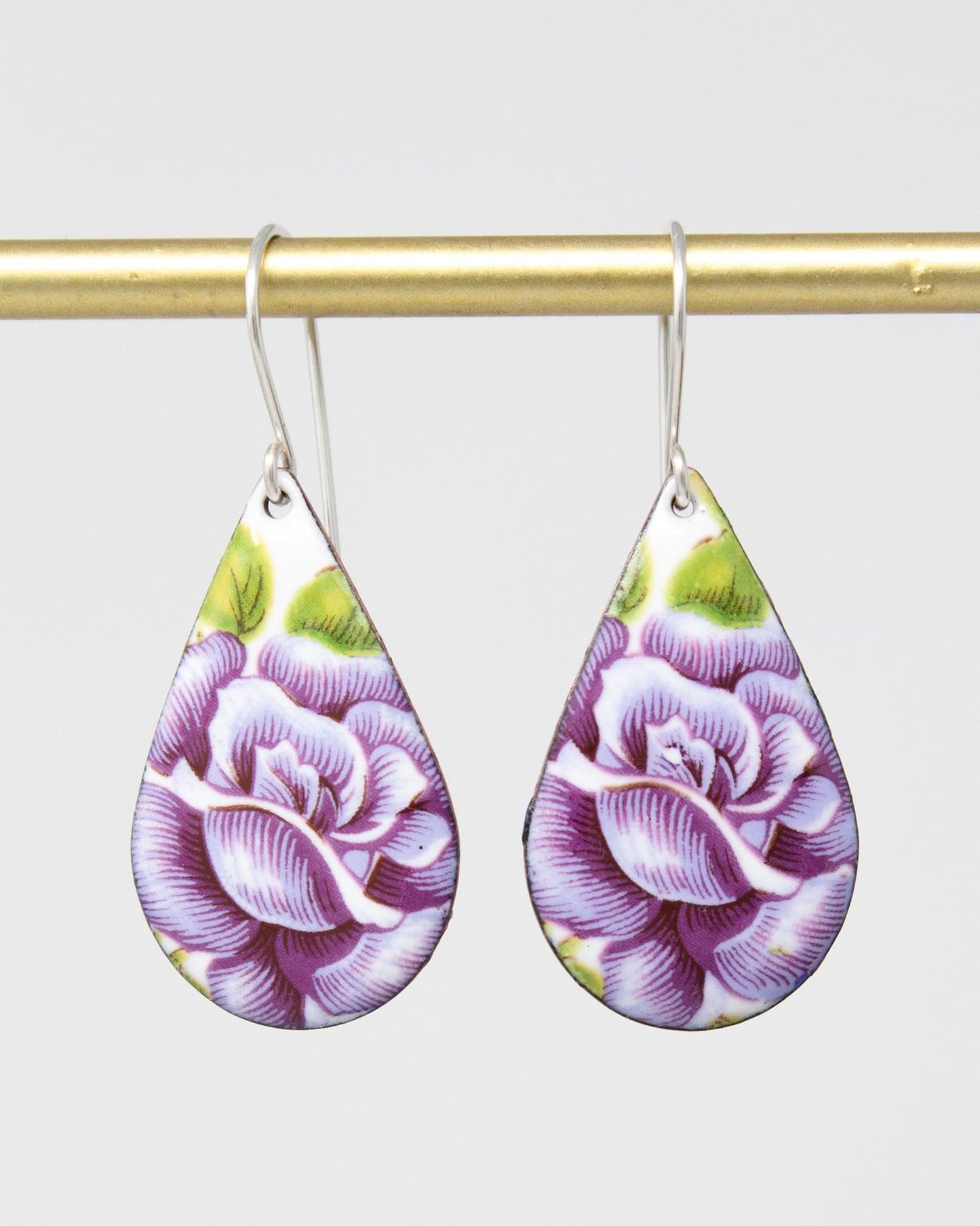 A pair of earrings with a floral design, featuring two teardrop-shaped pendants with purple and green floral patterns.