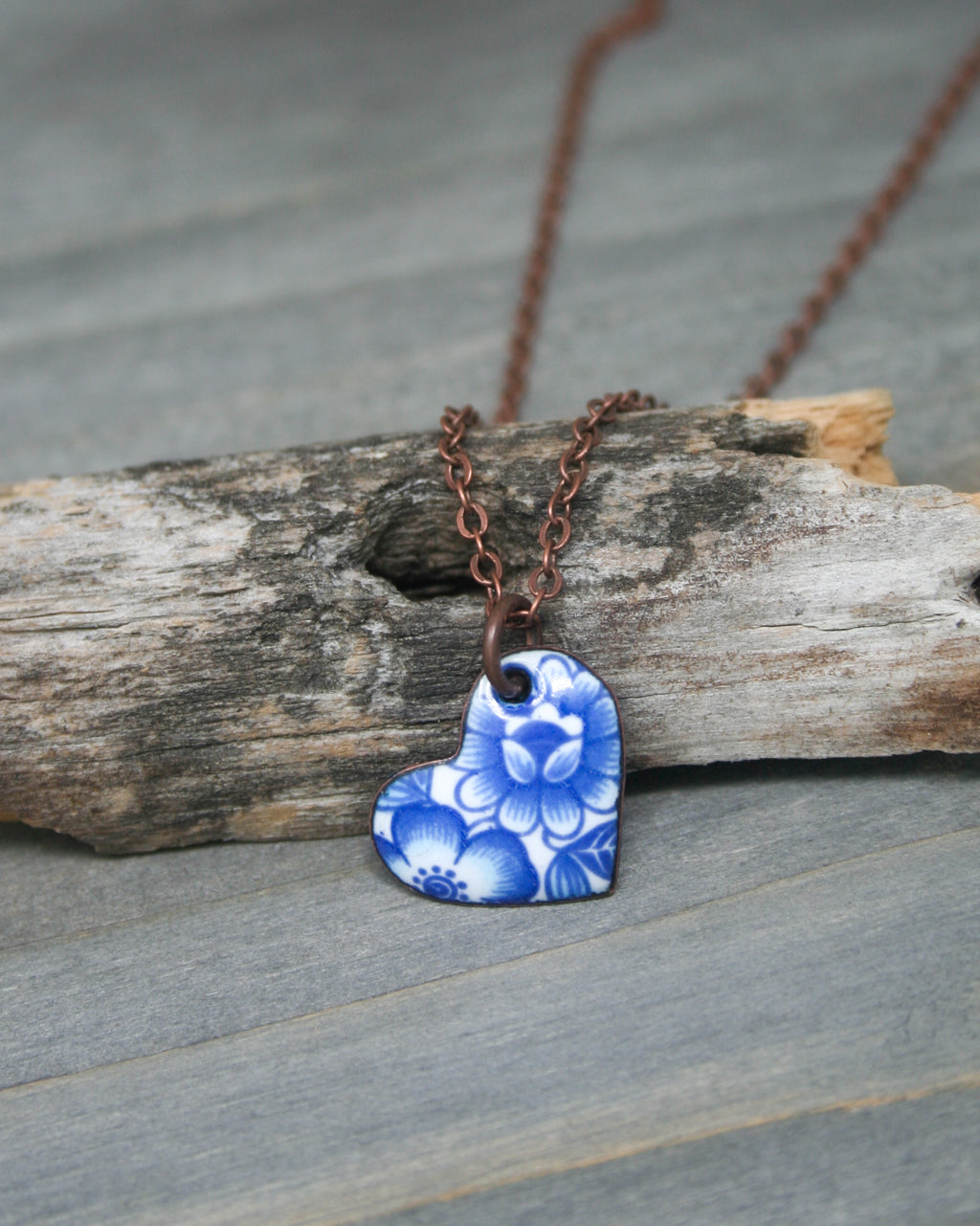 a blue and white heart shaped pendant on a brown chain