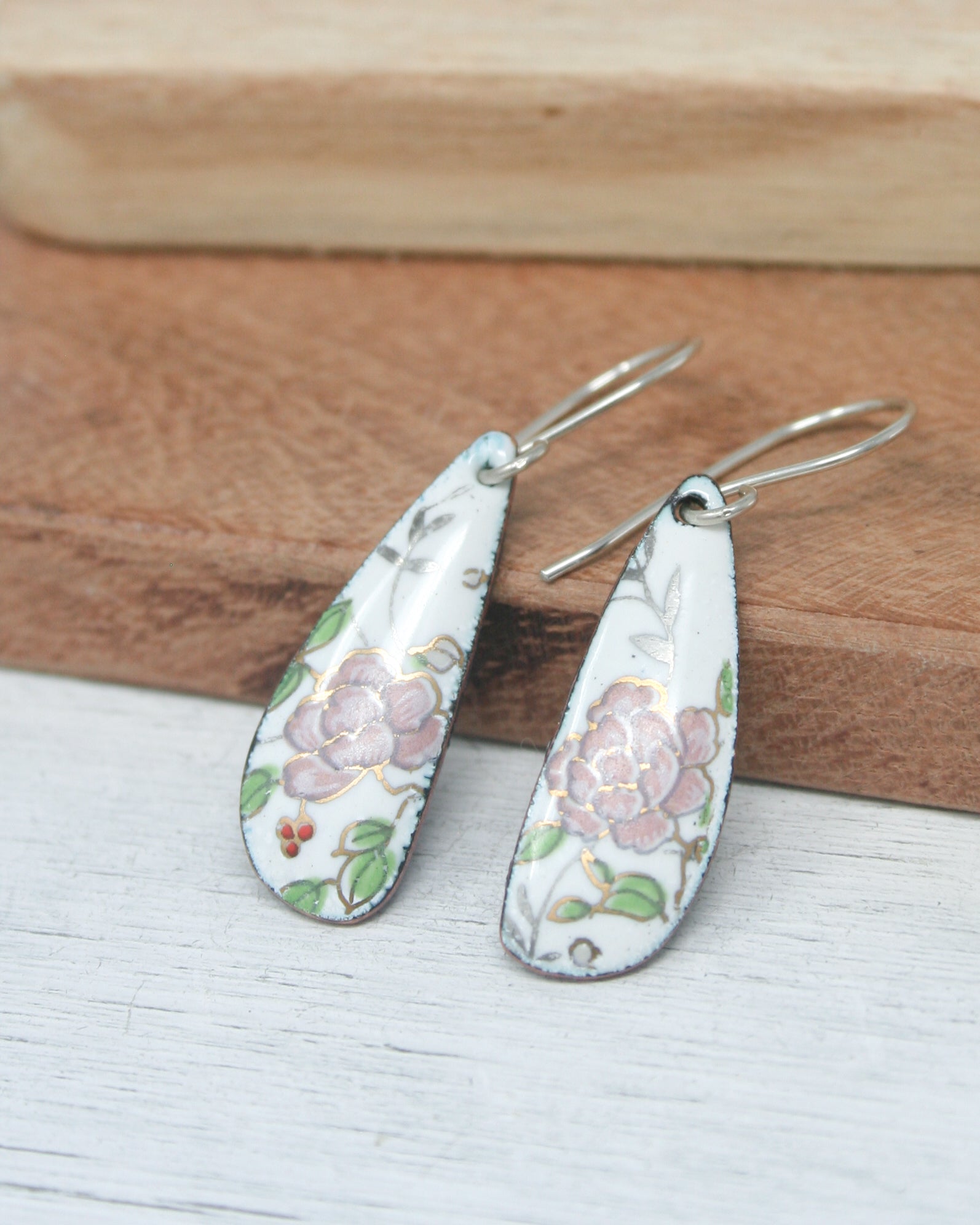 a pair of earrings sitting on top of a wooden board