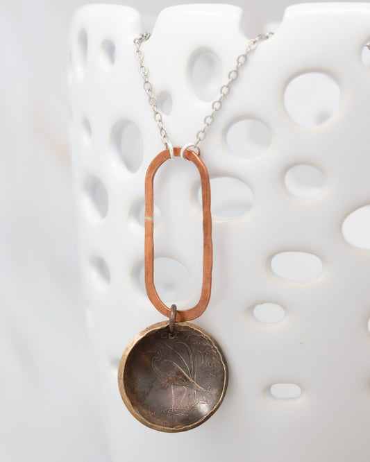 A necklace with a circular pendant featuring a floral design, hanging from a chain.