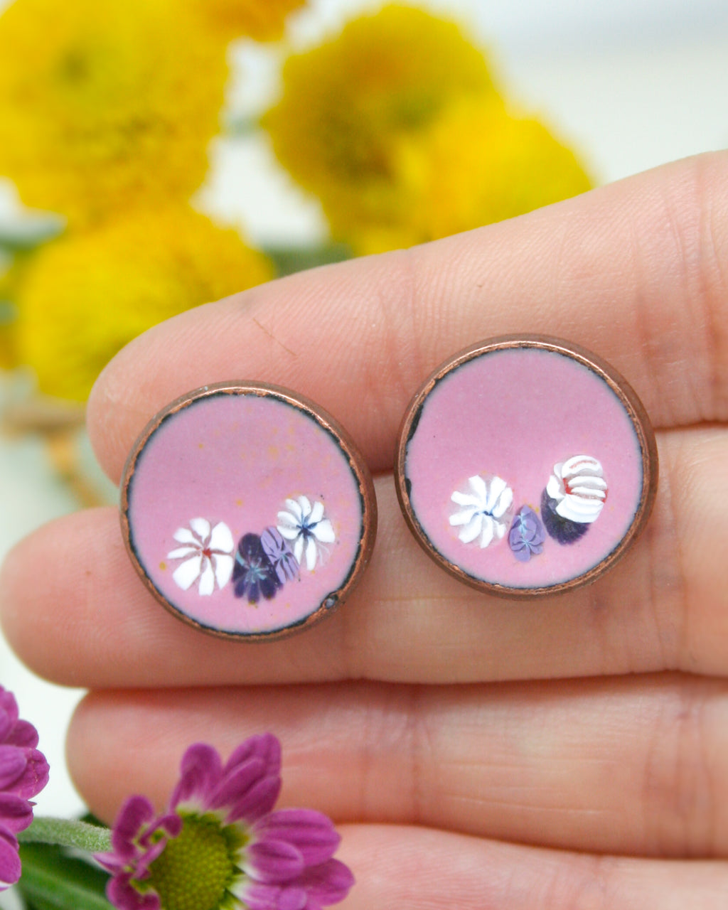 a hand holding a pair of pink and white flowers