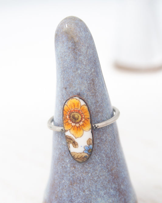 A ring with a floral design on it, placed on a blue ceramic stand.
