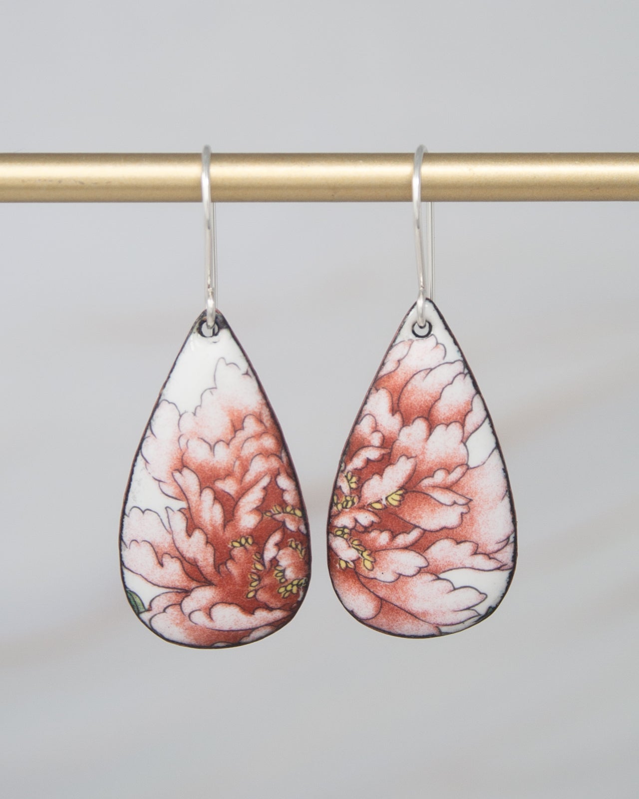 A pair of earrings with a floral design, featuring a combination of pink and white colors.