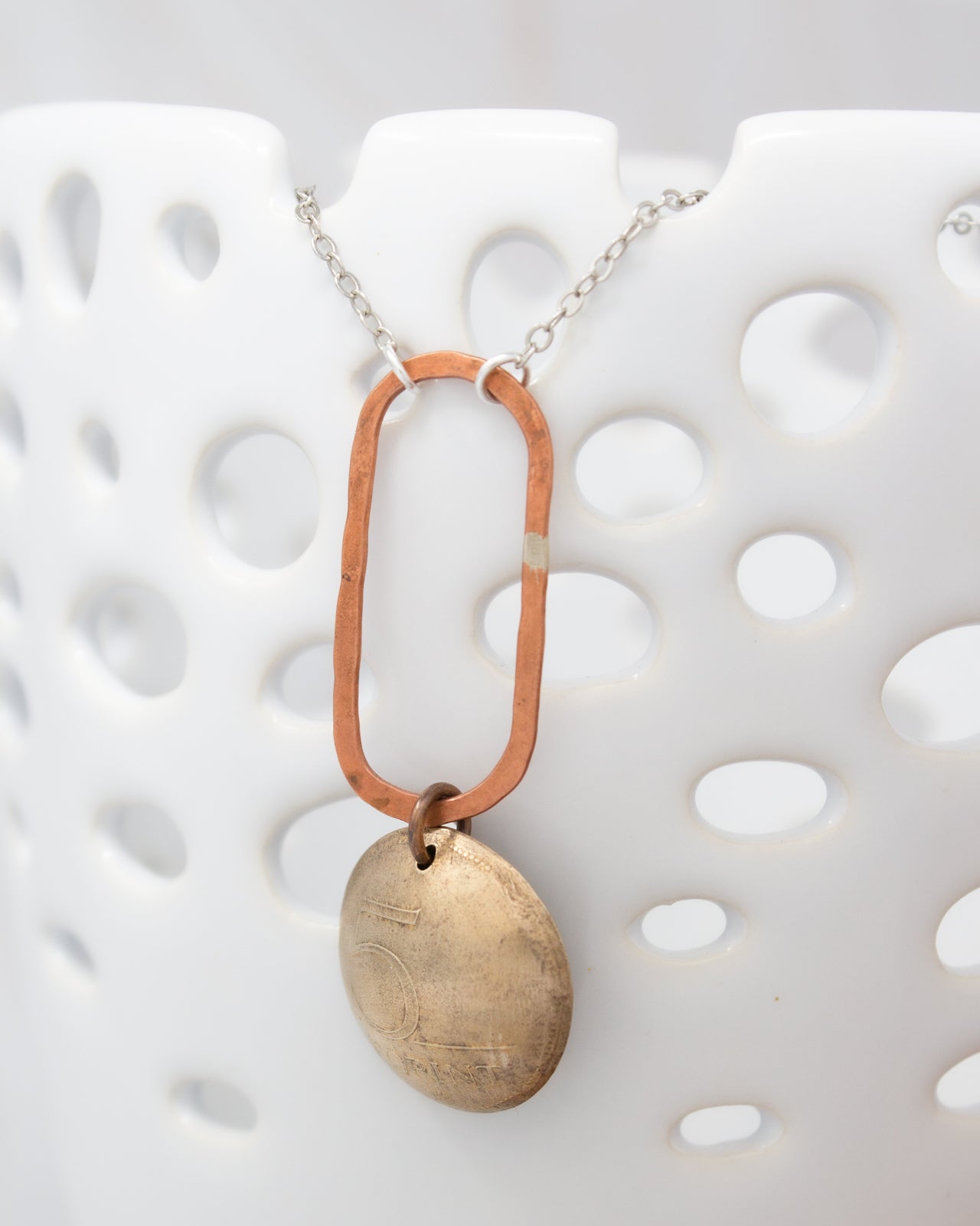 A necklace with a circular pendant and a chain is displayed against a white background.