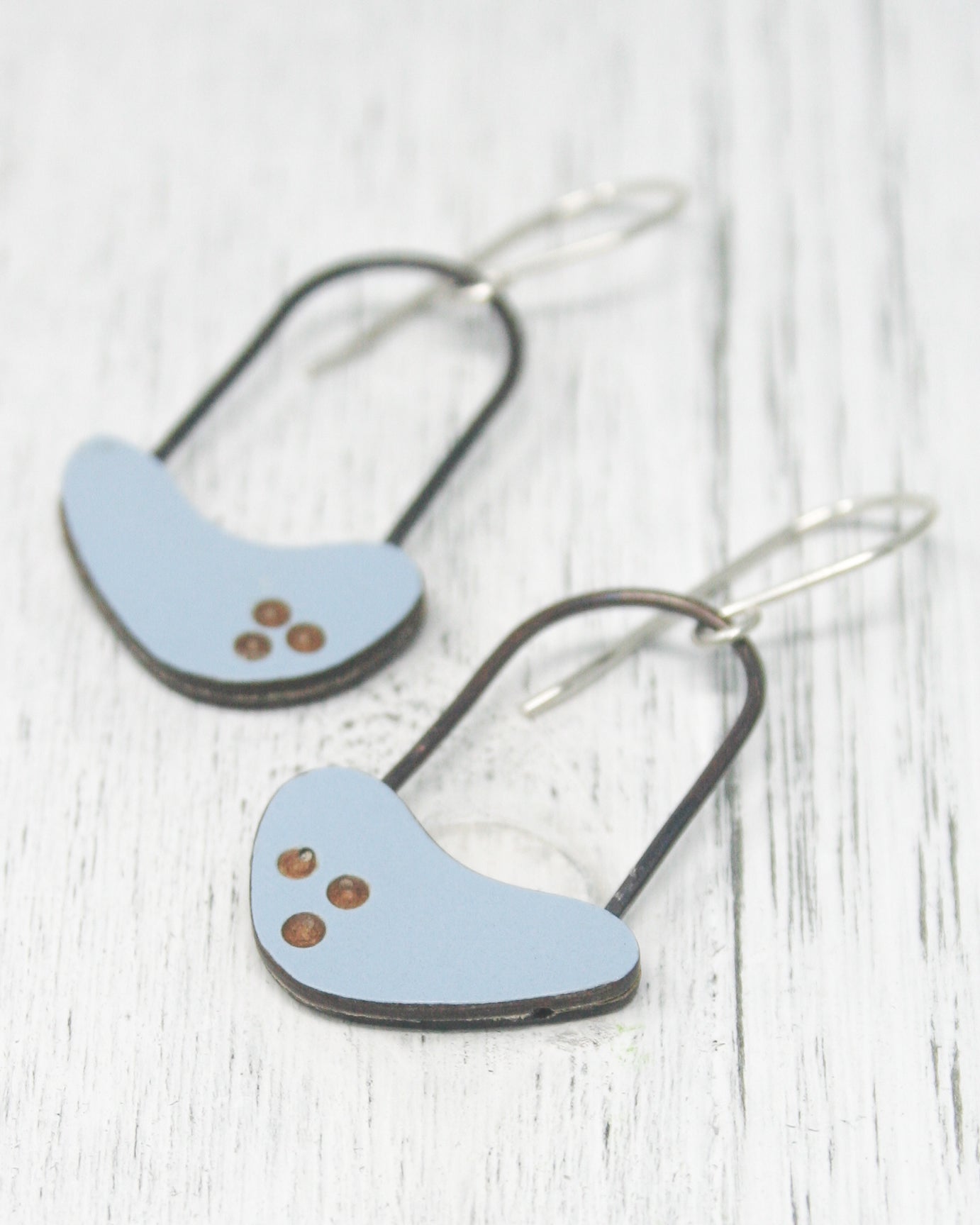 A pair of blue earrings with three small circular stones on the surface.