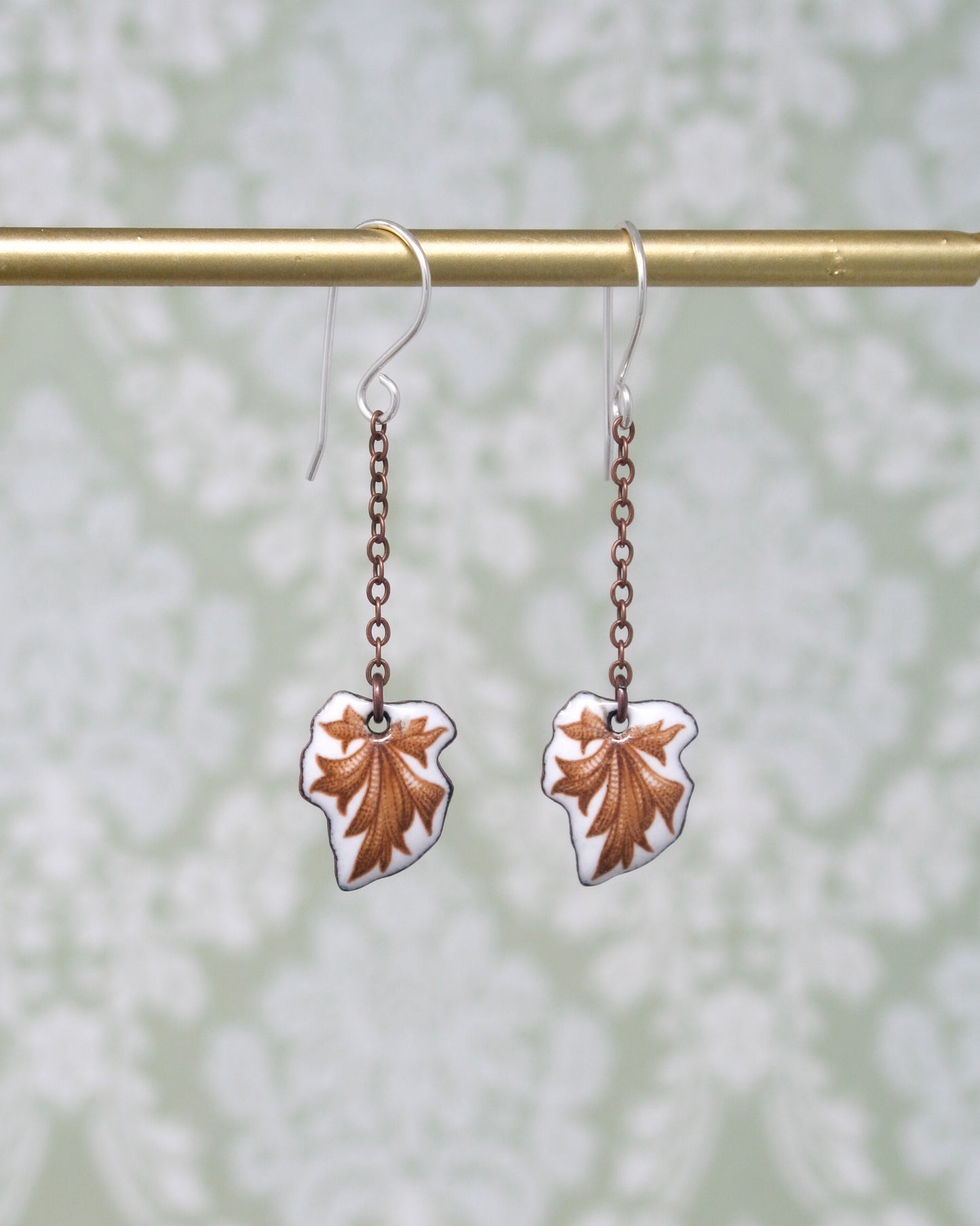 a pair of earrings hanging from a metal bar